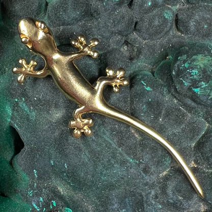 A solid yellow gold gecko lizard pendant with a hidden bail.
