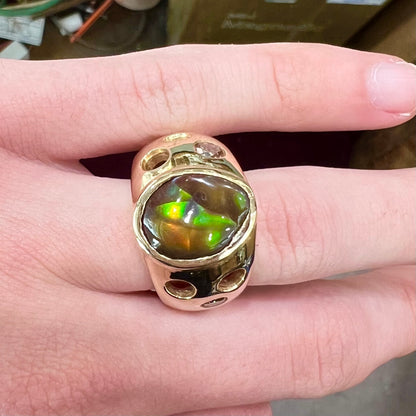 Men's rainbow fire agate ring set in yellow gold with champagne diamonds.  The ring style has holes.