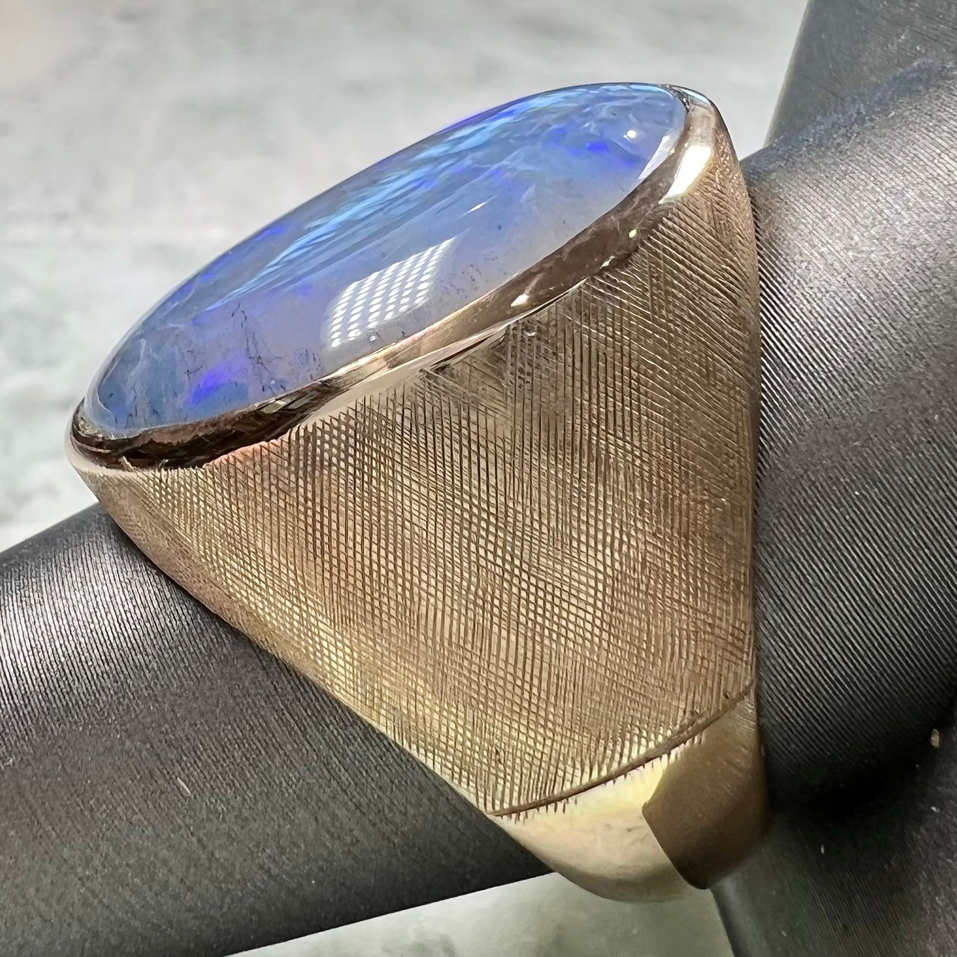 A Lightning Ridge black opal men's ring in solid yellow textured gold.