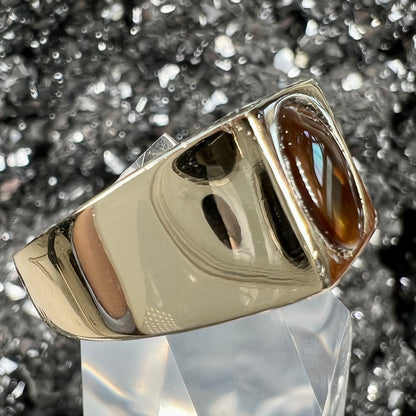 A men's yellow gold flush set fire agate solitaire ring.  The fire agate displays flashes of green, orange, and yellow.