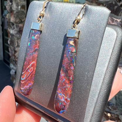 A pair of yellow gold cap Koroit boulder opal dangle earrings.  Purple highlights are seen.