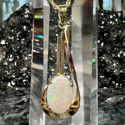 A handmade gold drop pendant set with an oval cabochon cut white crystal opal.