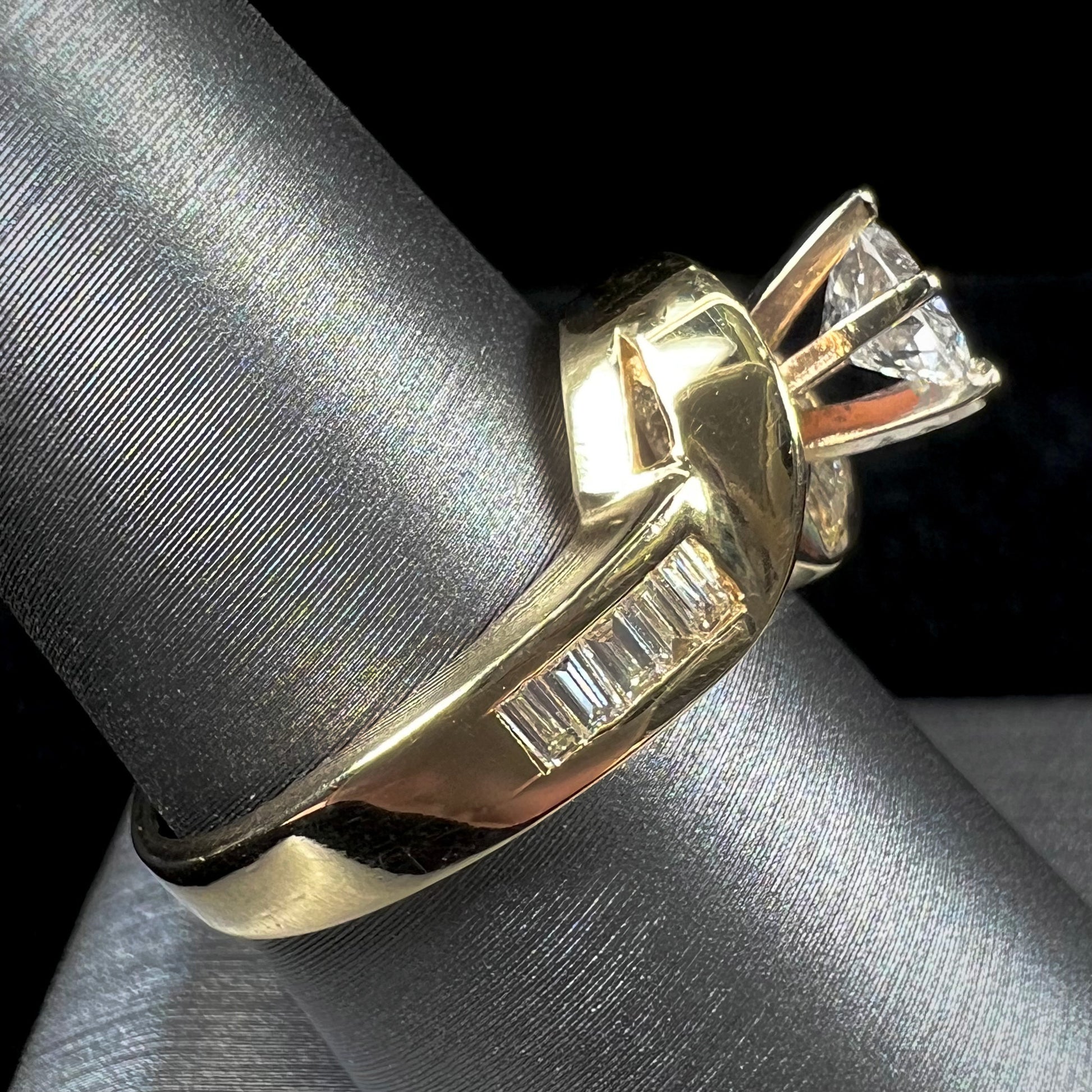 A ladies' yellow gold engagement ring set with a 0.77ct oval cut diamond and baguette cut diamond accents.