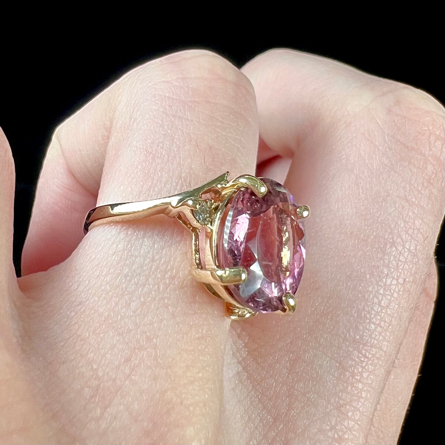 A ladies' yellow gold, faceted oval cut purple tourmaline ring set with diamond accents.