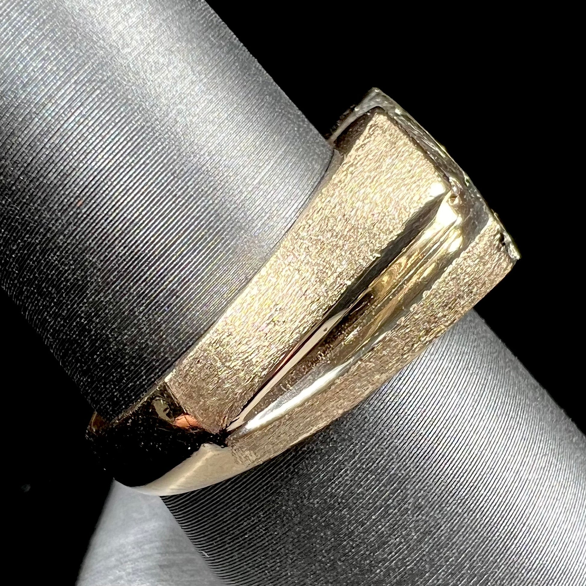A men's yellow gold ring channel set with princess cut blue sapphires and diamonds.