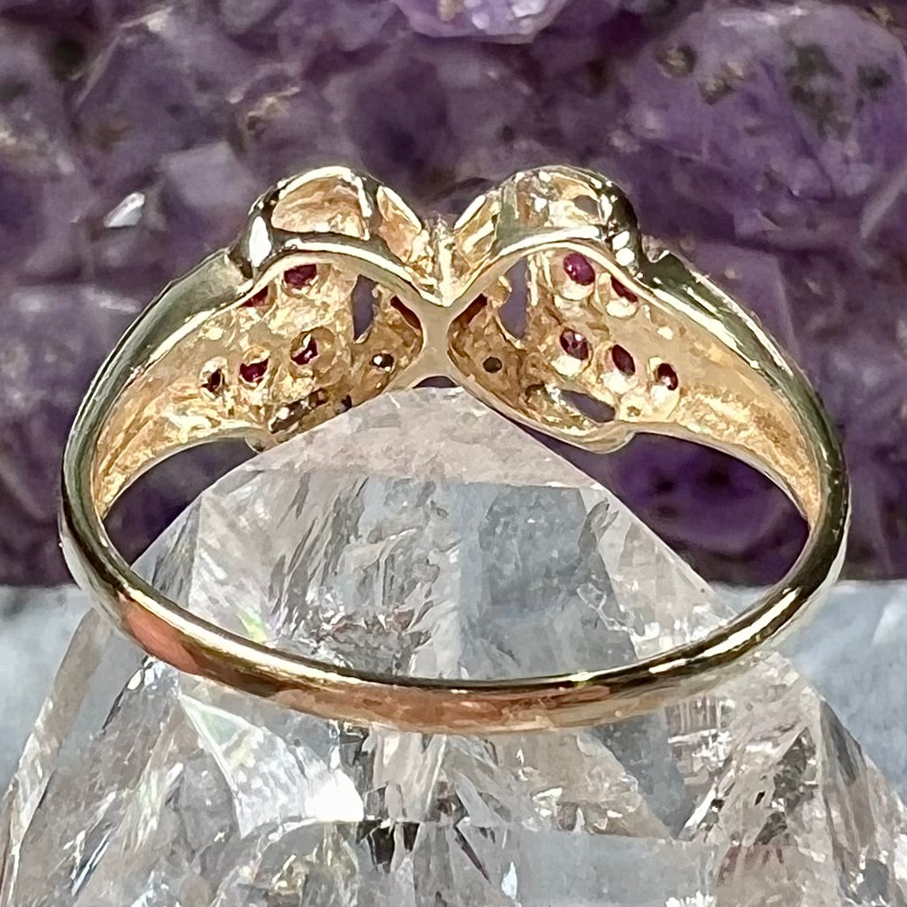 A yellow gold princess cut ruby ring set with round ruby and diamond accents.