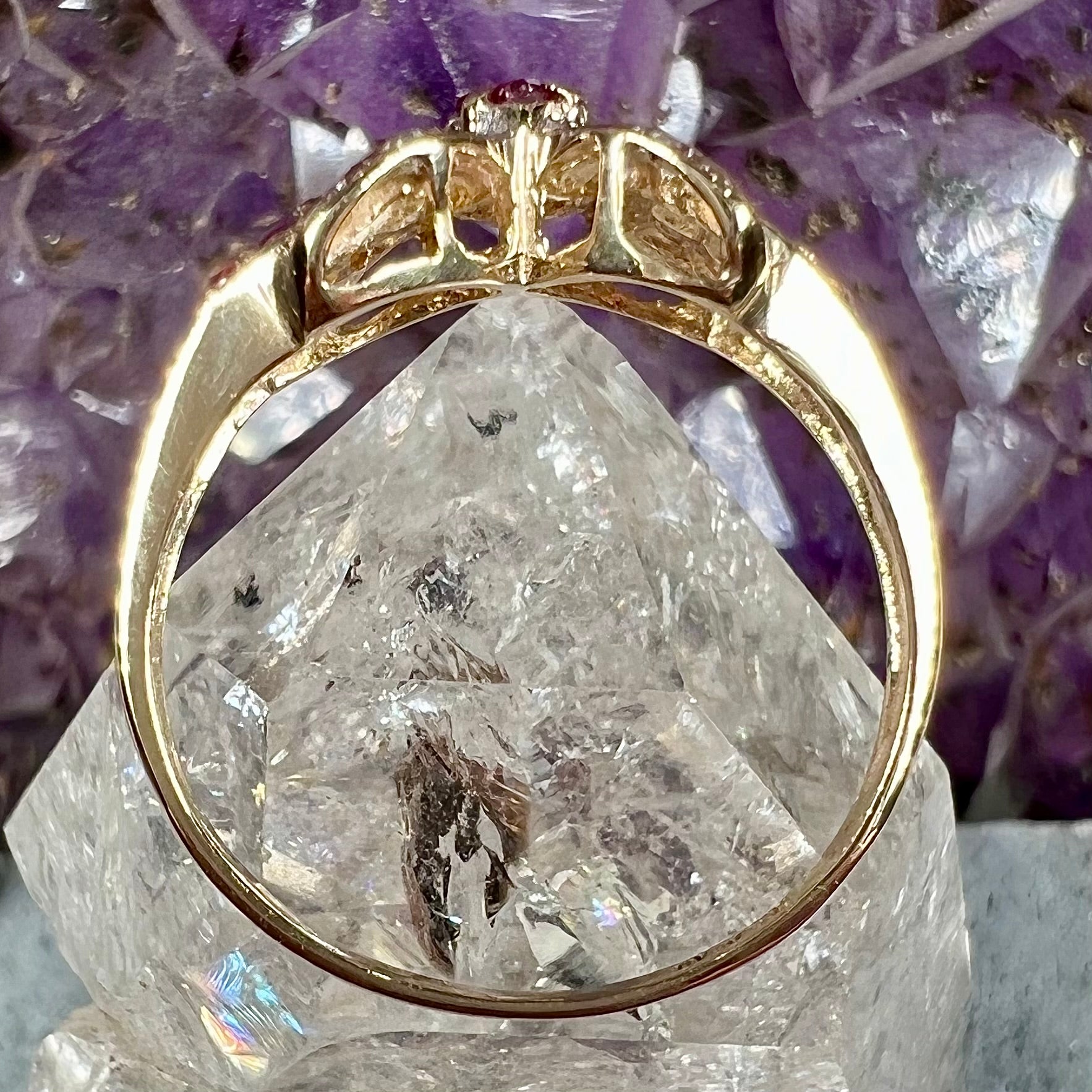 A yellow gold princess cut ruby ring set with round ruby and diamond accents.