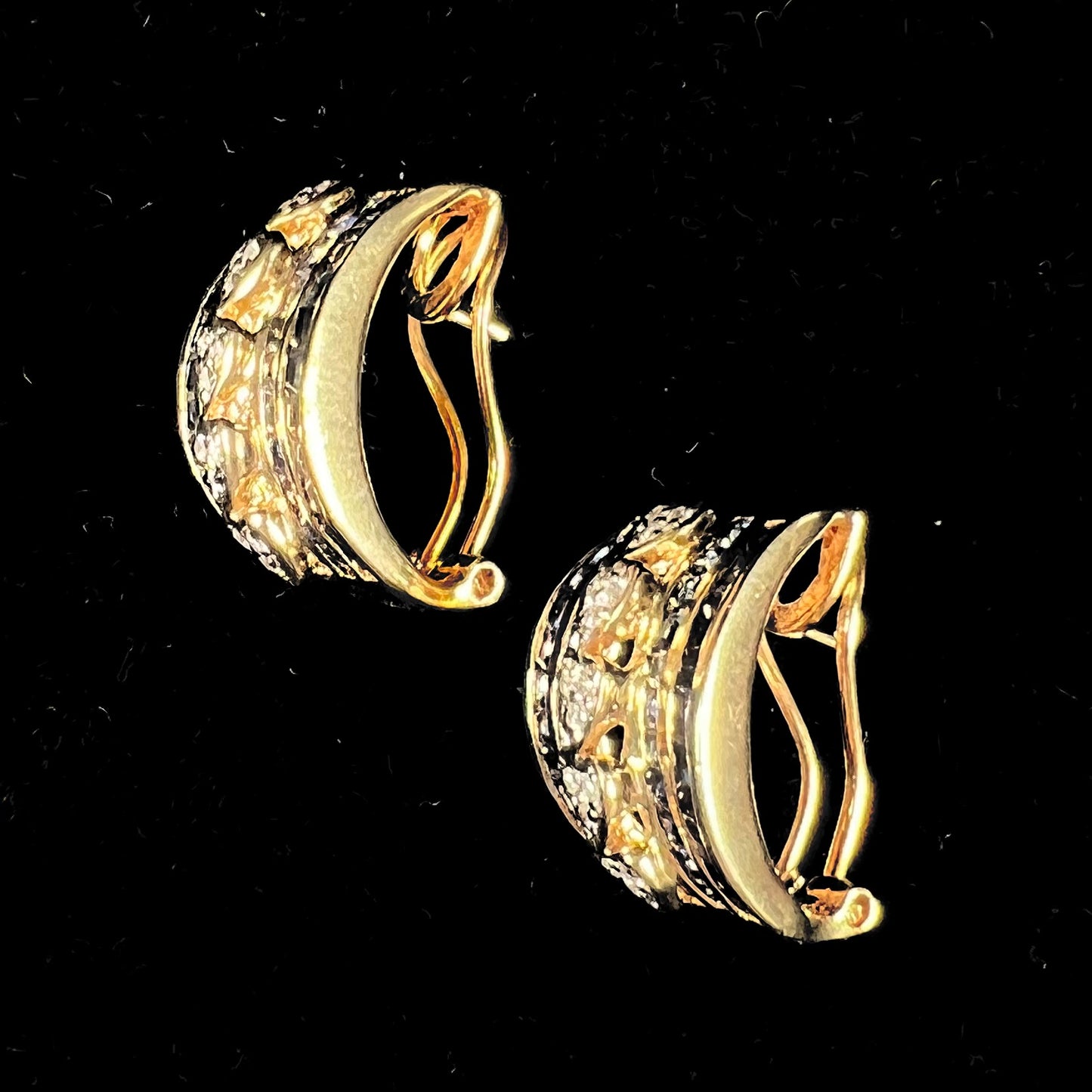 A pair of gold omega back earrings channel set with blue sapphires and heards set with diamonds.