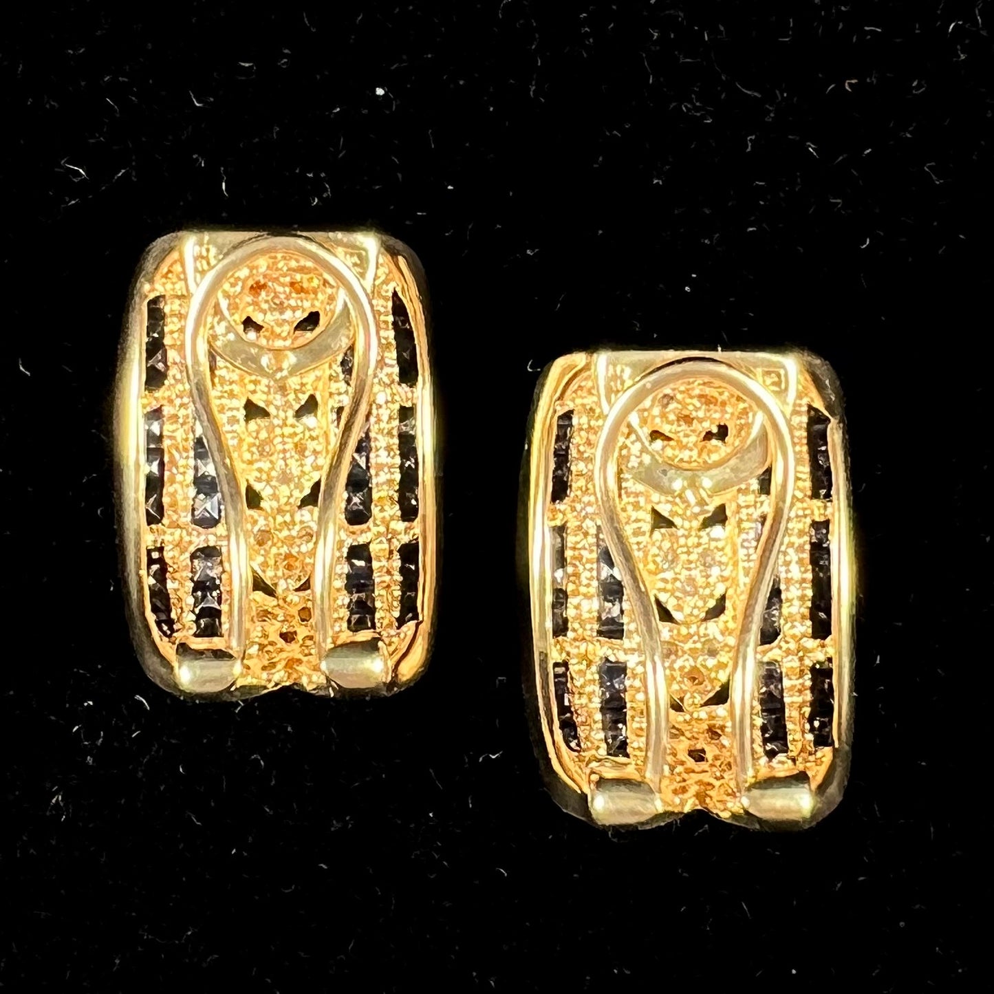 A pair of gold omega back earrings channel set with blue sapphires and heards set with diamonds.