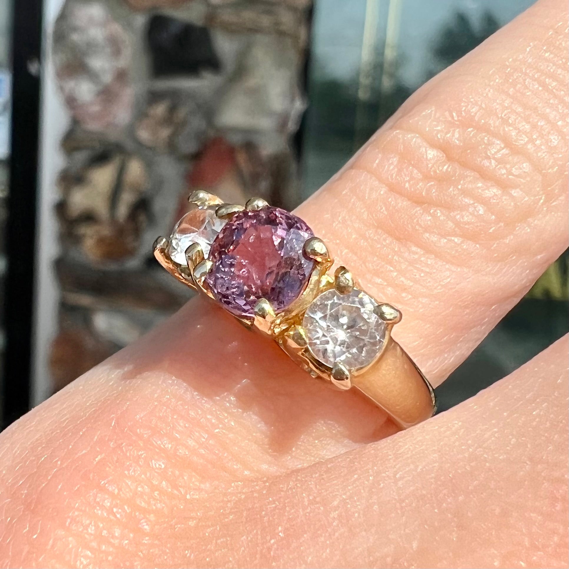 A yellow gold three stone ring set with two round cut white zircons and one cushion cut purple spinel.