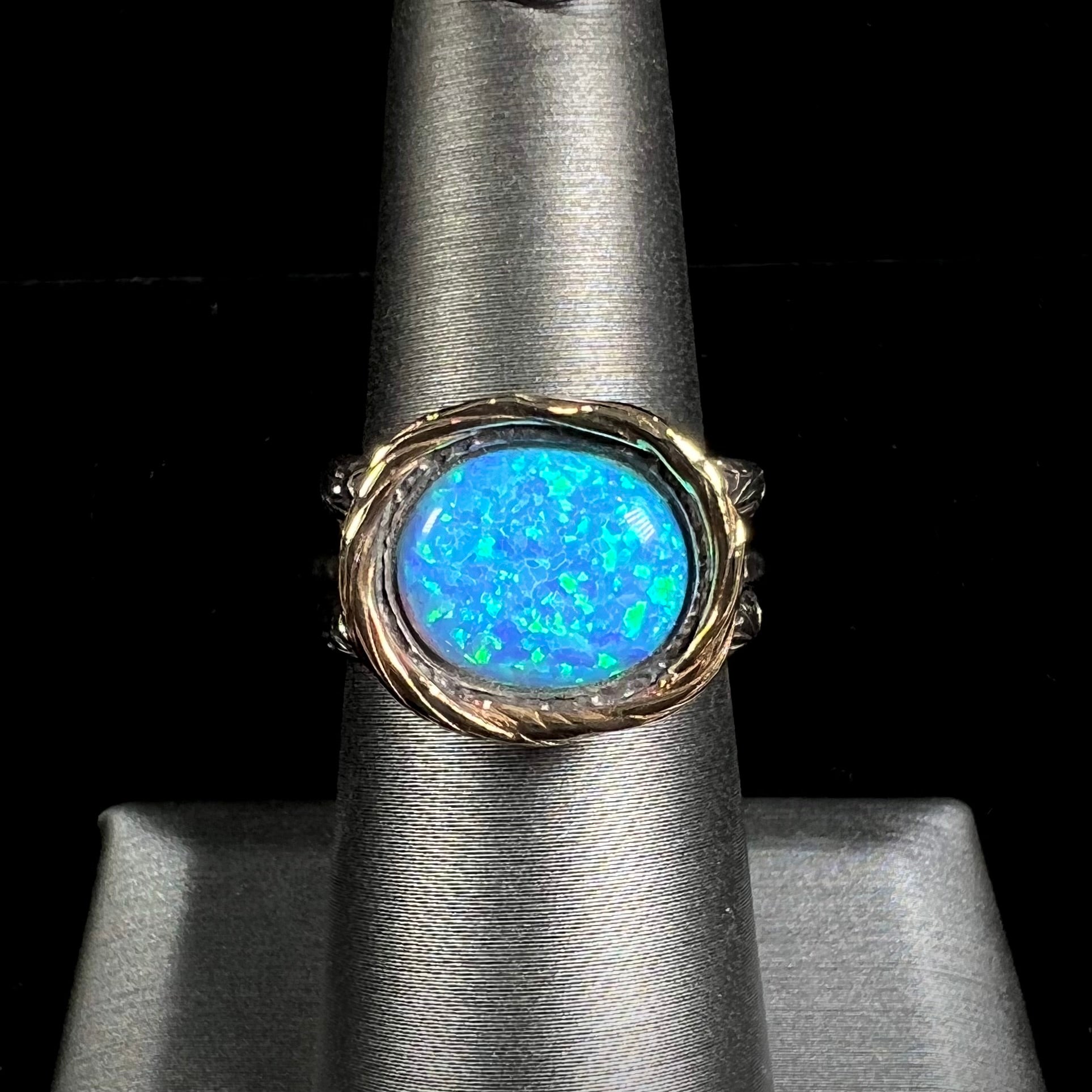 A filigree etched two tone silver and gold spinner ring set with a lab created black opal.