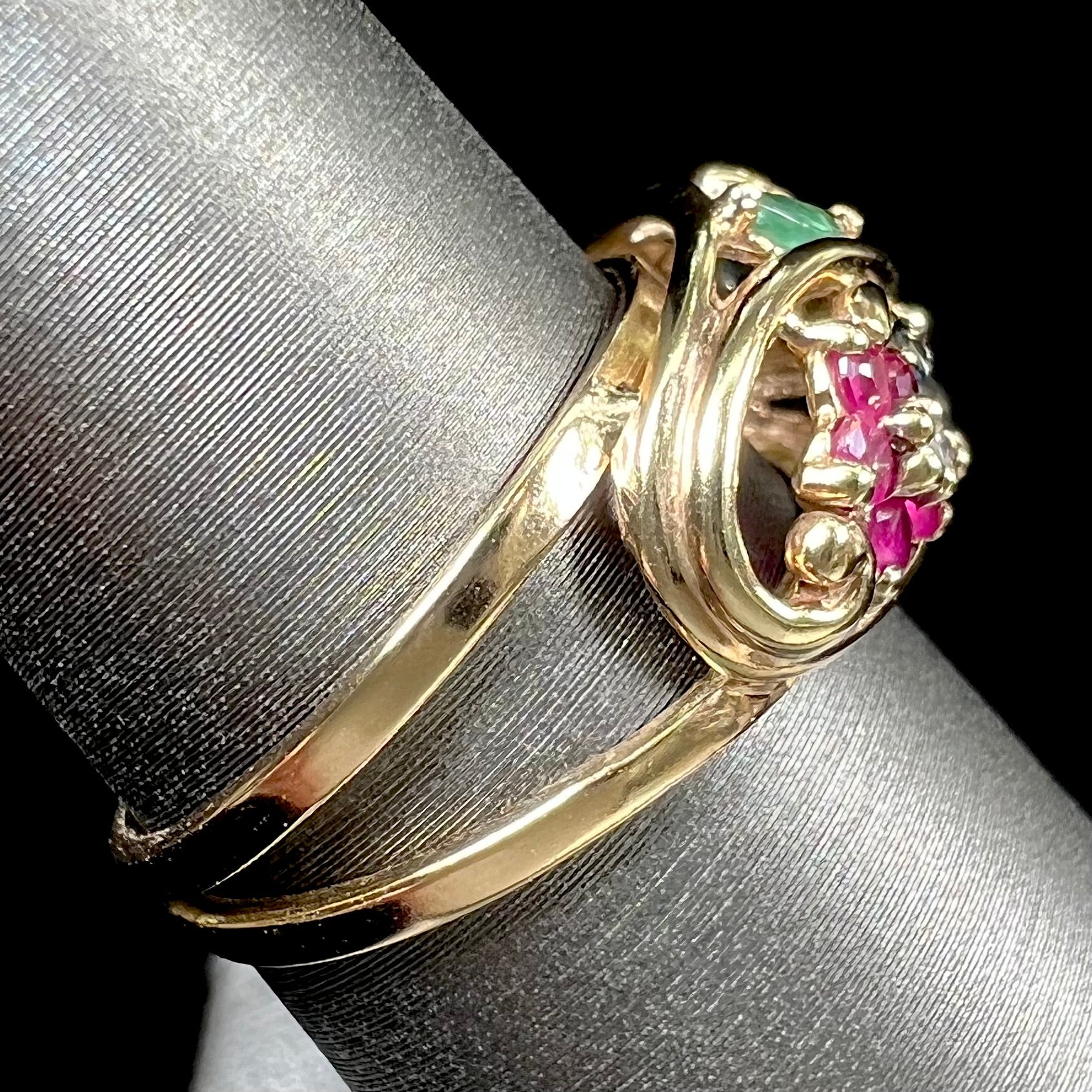 A yellow gold ladies' ring featuring the motif of a flower with leaves set with emeralds, rubies, sapphires, and a  diamond.