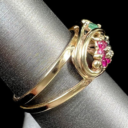 A yellow gold ladies' ring featuring the motif of a flower with leaves set with emeralds, rubies, sapphires, and a  diamond.