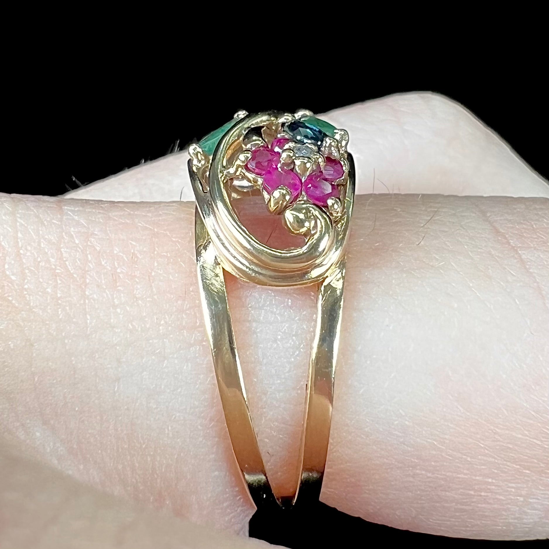 A yellow gold ladies' ring featuring the motif of a flower with leaves set with emeralds, rubies, sapphires, and a  diamond.