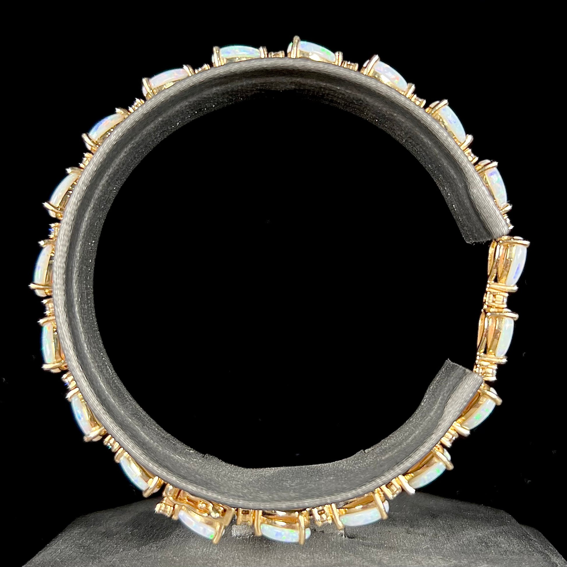 A ladies' gold tennis style bracelet set with pear shaped white crystal opals and diamonds.