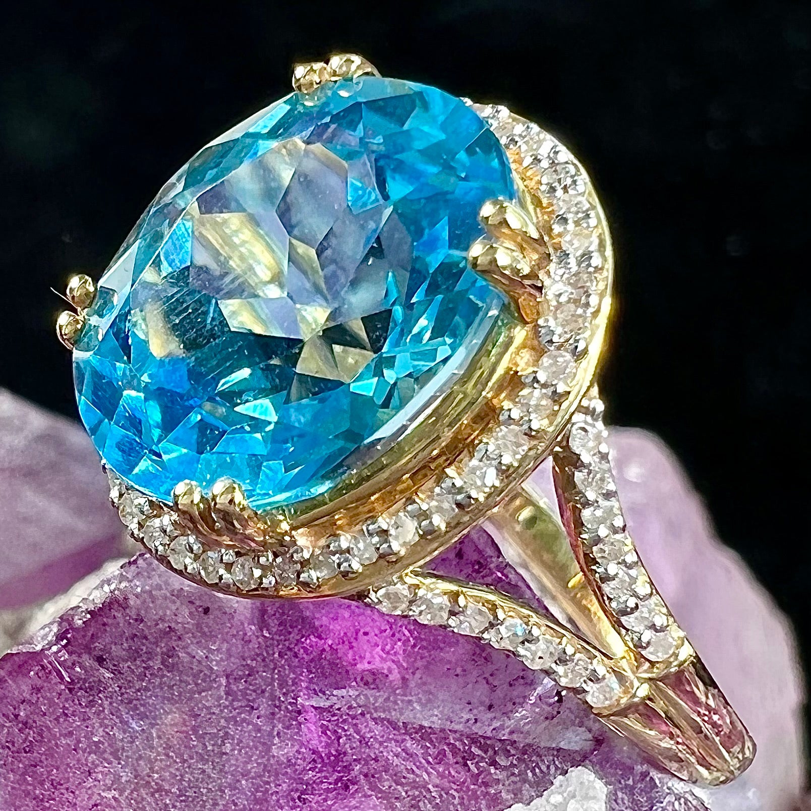 An oval cut Swiss blue topaz and diamond pave split shank ring in yellow gold.