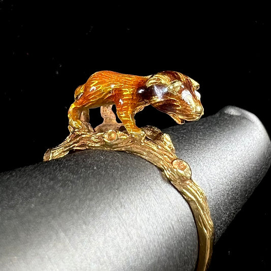 An estate 18kt yellow gold ring featuring a 3D enameled lion walking on a tree branch.