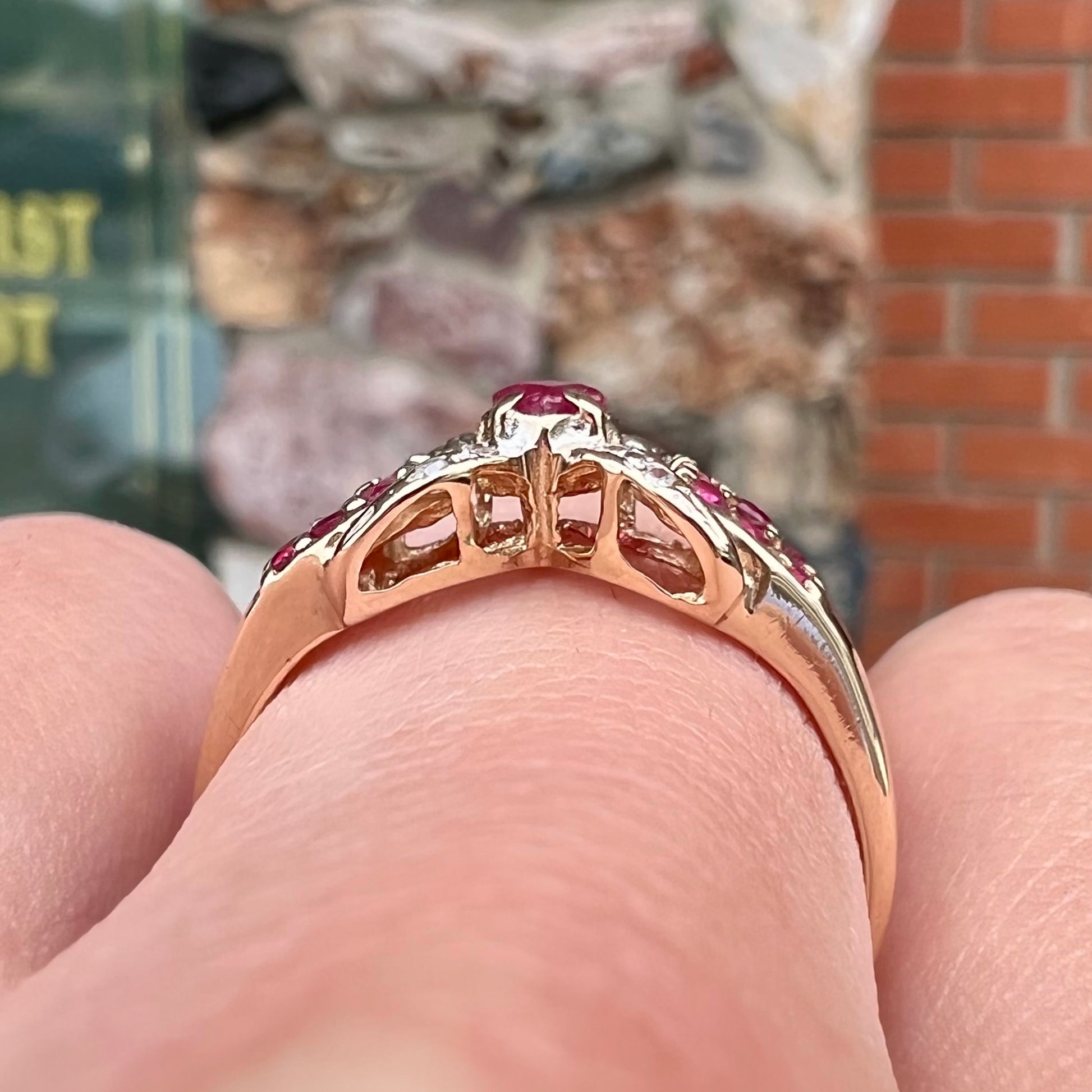 A yellow gold princess cut ruby ring set with round ruby and diamond accents.