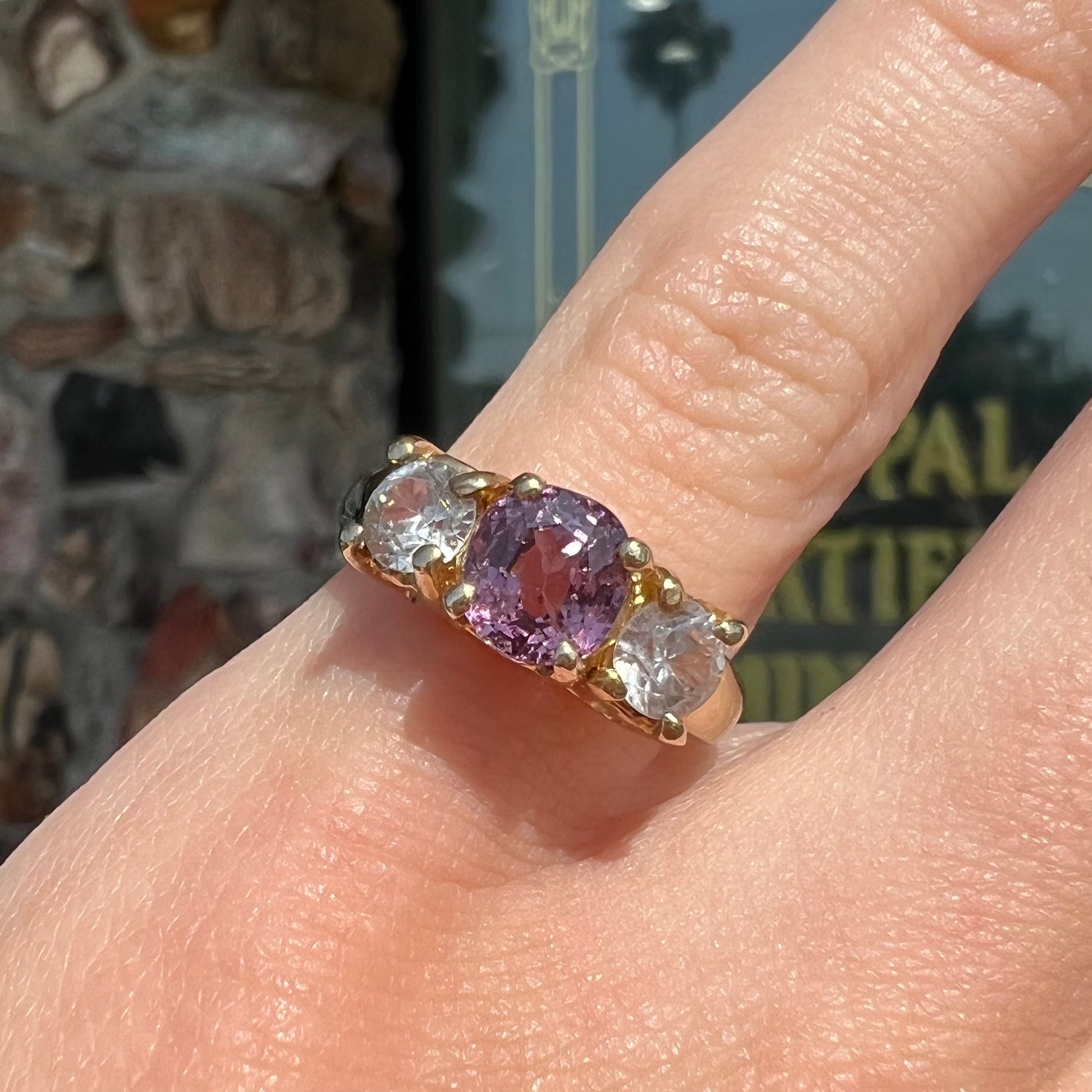 A yellow gold three stone ring set with two round cut white zircons and one cushion cut purple spinel.