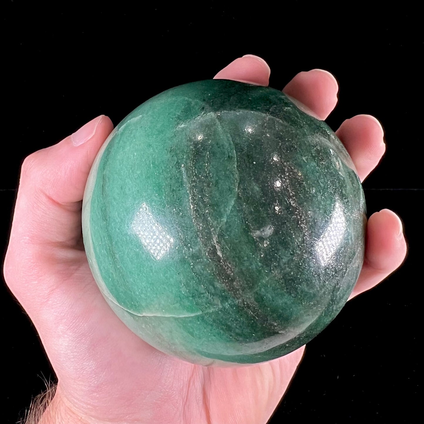 A stone sphere carved from natural green aventurine quartz with containing mica inclusions.