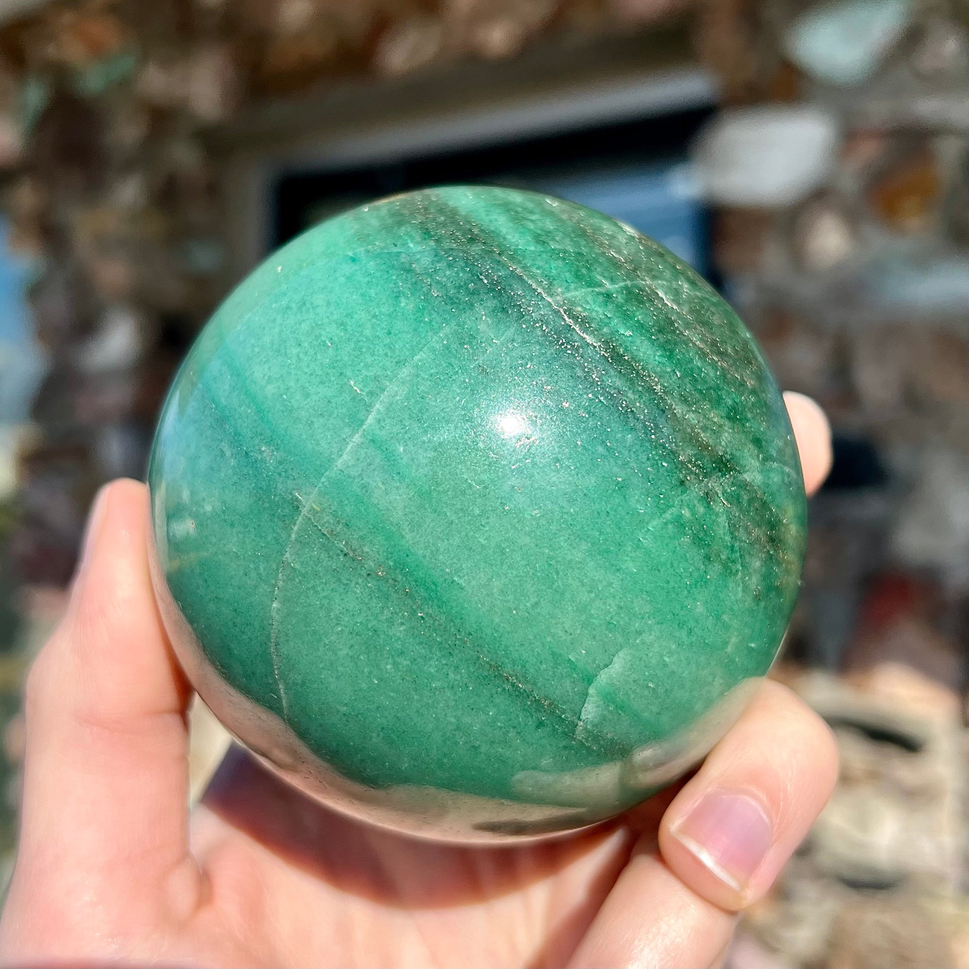 A stone sphere carved from natural green aventurine quartz with containing mica inclusions.