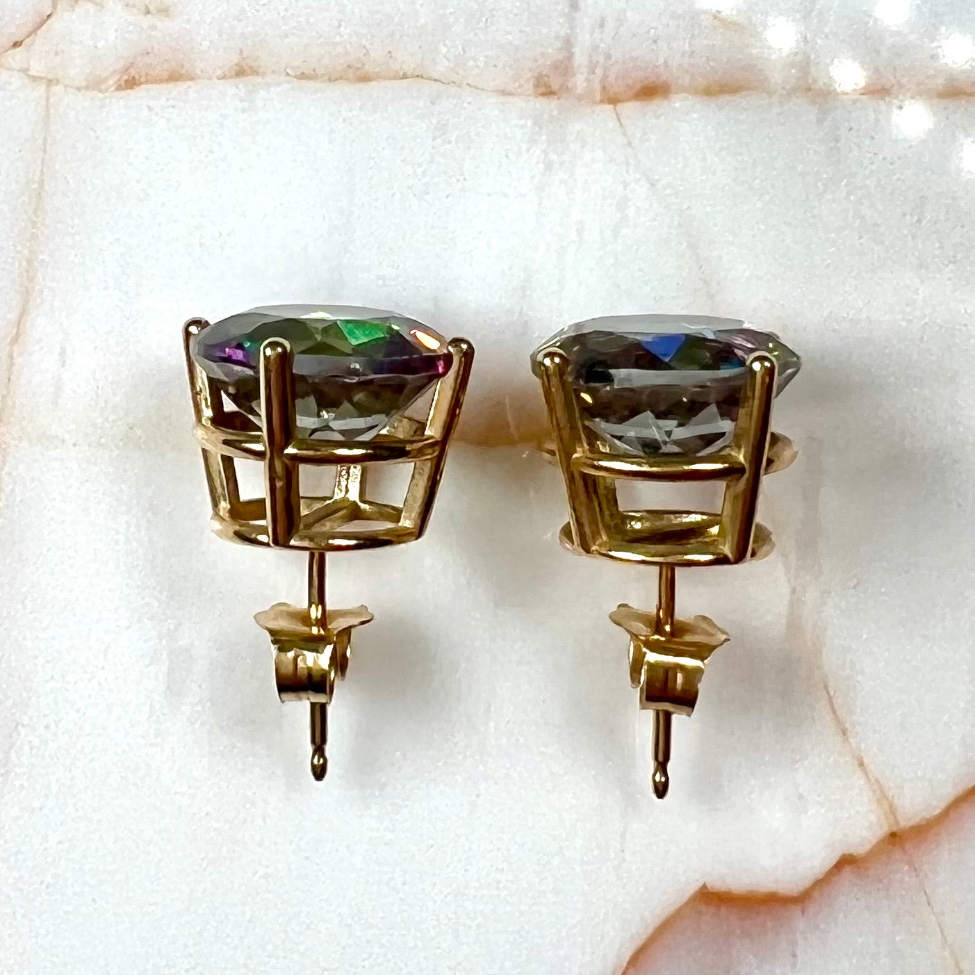 Round cut mystic topaz stones set in yellow gold prong-set push-back earrings.
