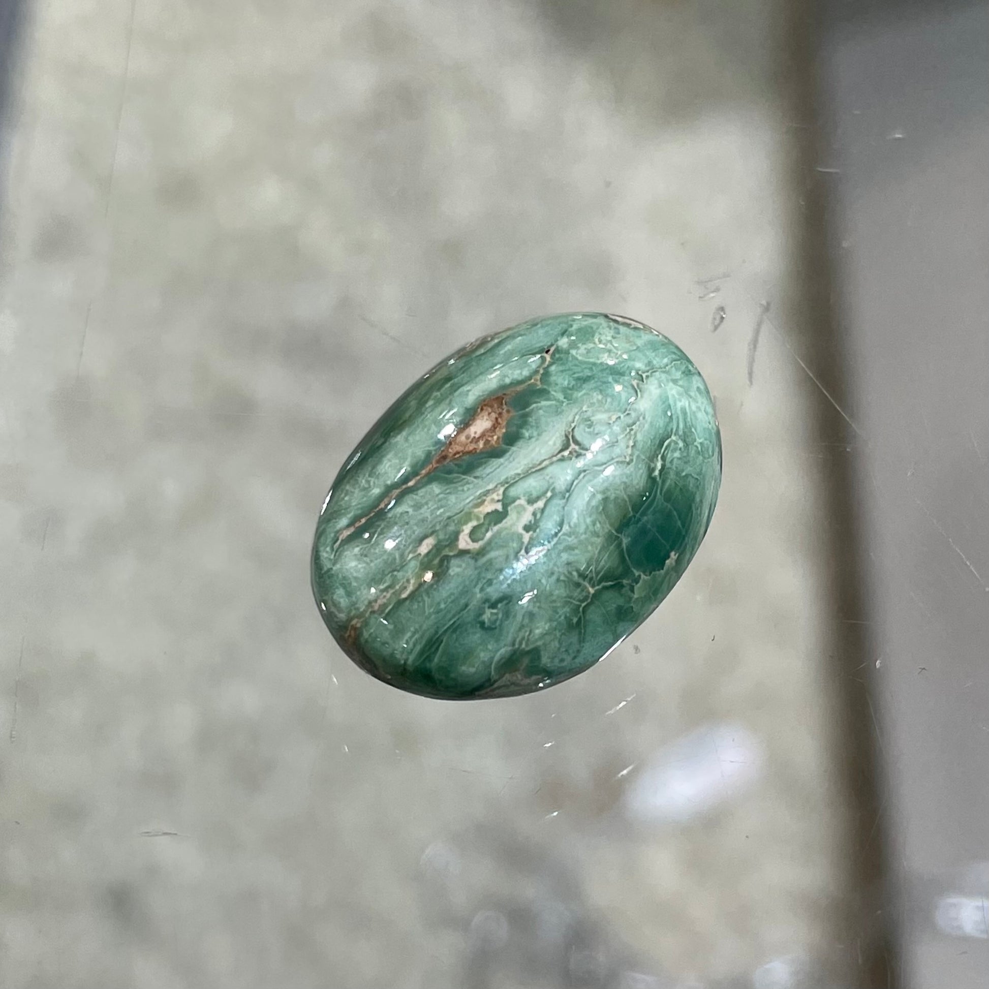 A loose, green oval cabochon cut turquoise stone from the Royston Mining District in Nevada.  Green color marbles around a light brown eye.