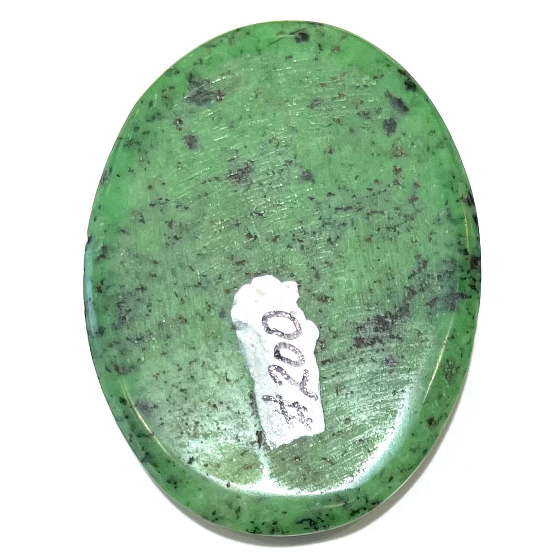 A loose, oval cabochon cut green zoisite stone with black spots.