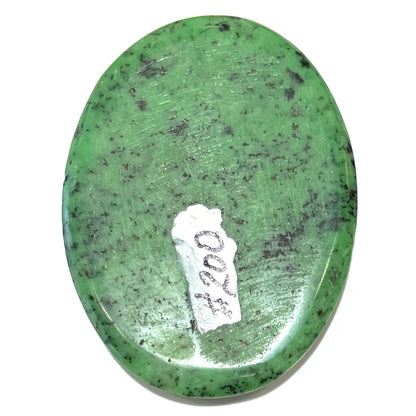 A loose, oval cabochon cut green zoisite stone with black spots.