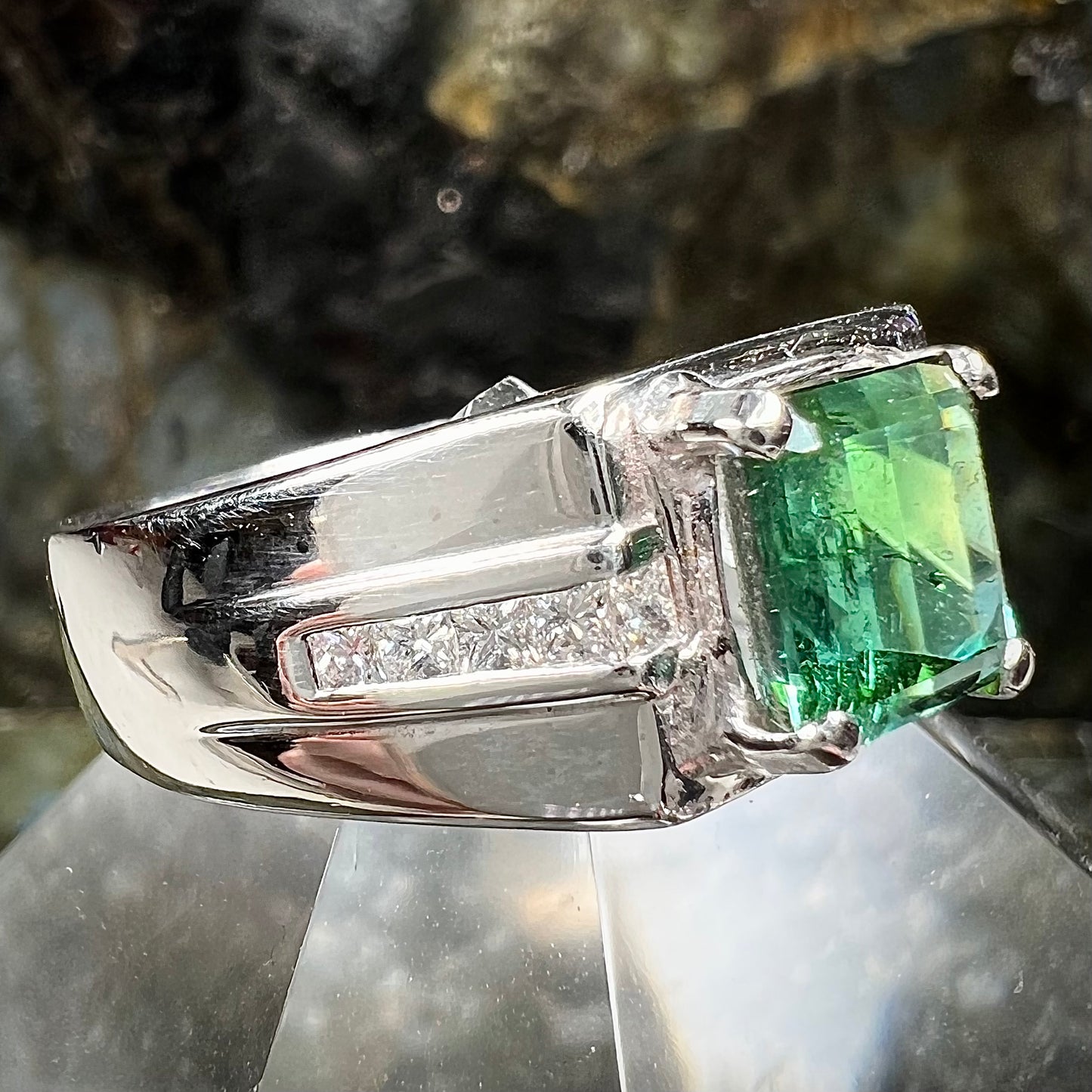 An 18k white gold green tourmaline and diamond men's ring.  The stones are princess cut.