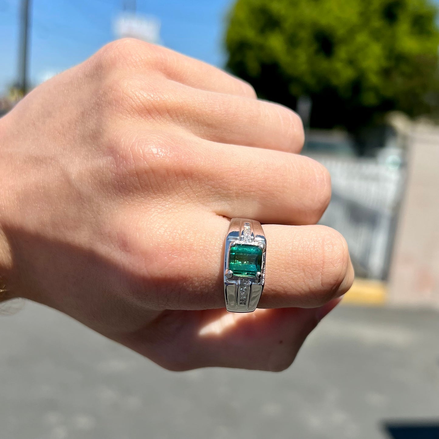 An 18k white gold green tourmaline and diamond men's ring.  The stones are princess cut.