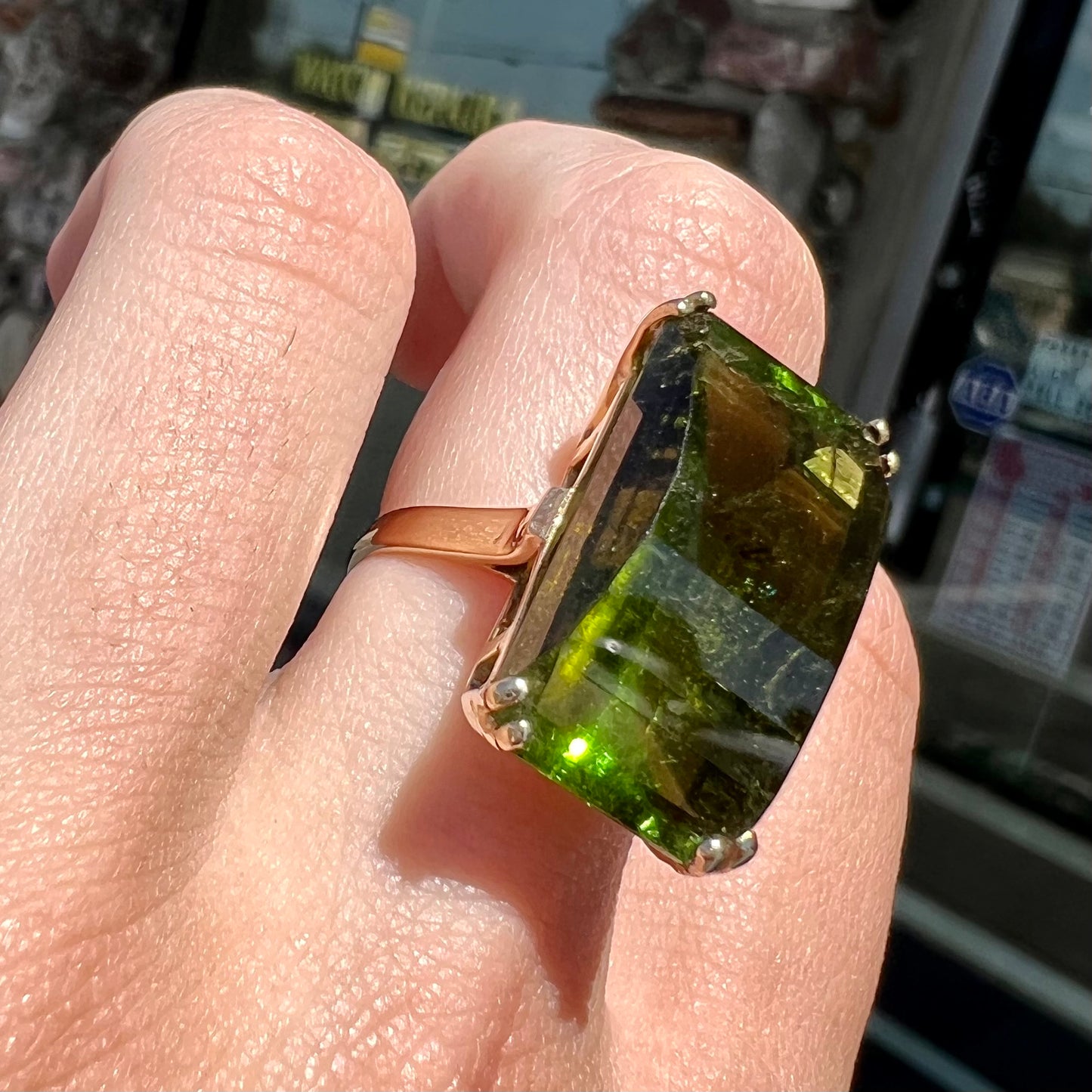 A faceted step-cut dark green tourmaline basket set solitaire ring cast in yellow gold.