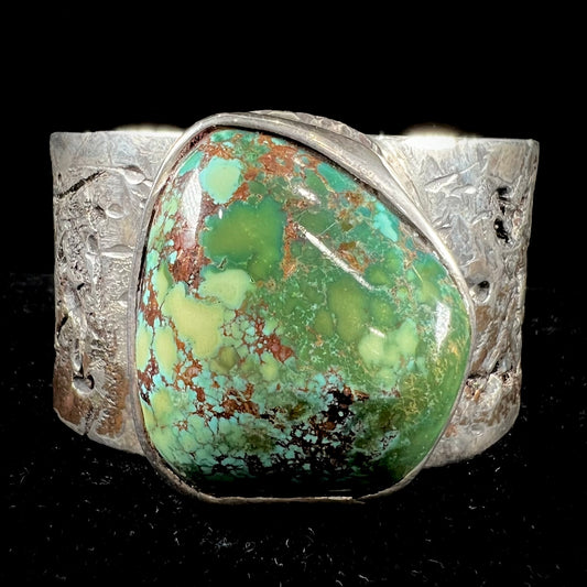 A men's sterling silver cuff bracelet infused with copper and set with a green turquoise stone from Carico Lake, Nevada.