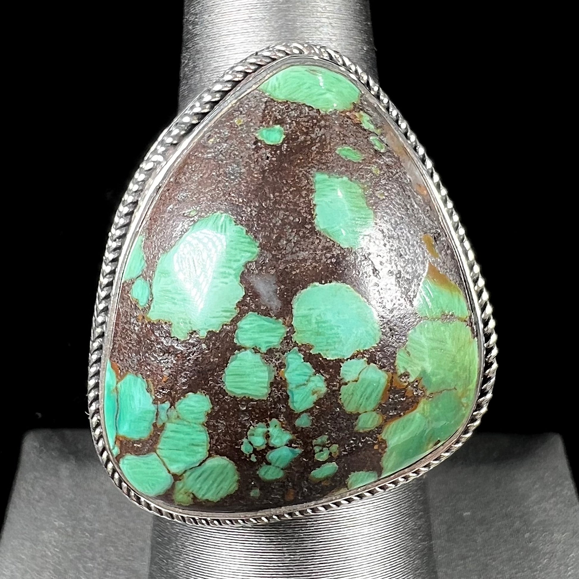 A sterling silver ring bezel set with a green spotted turquoise stone from Carico Lake, Nevada.