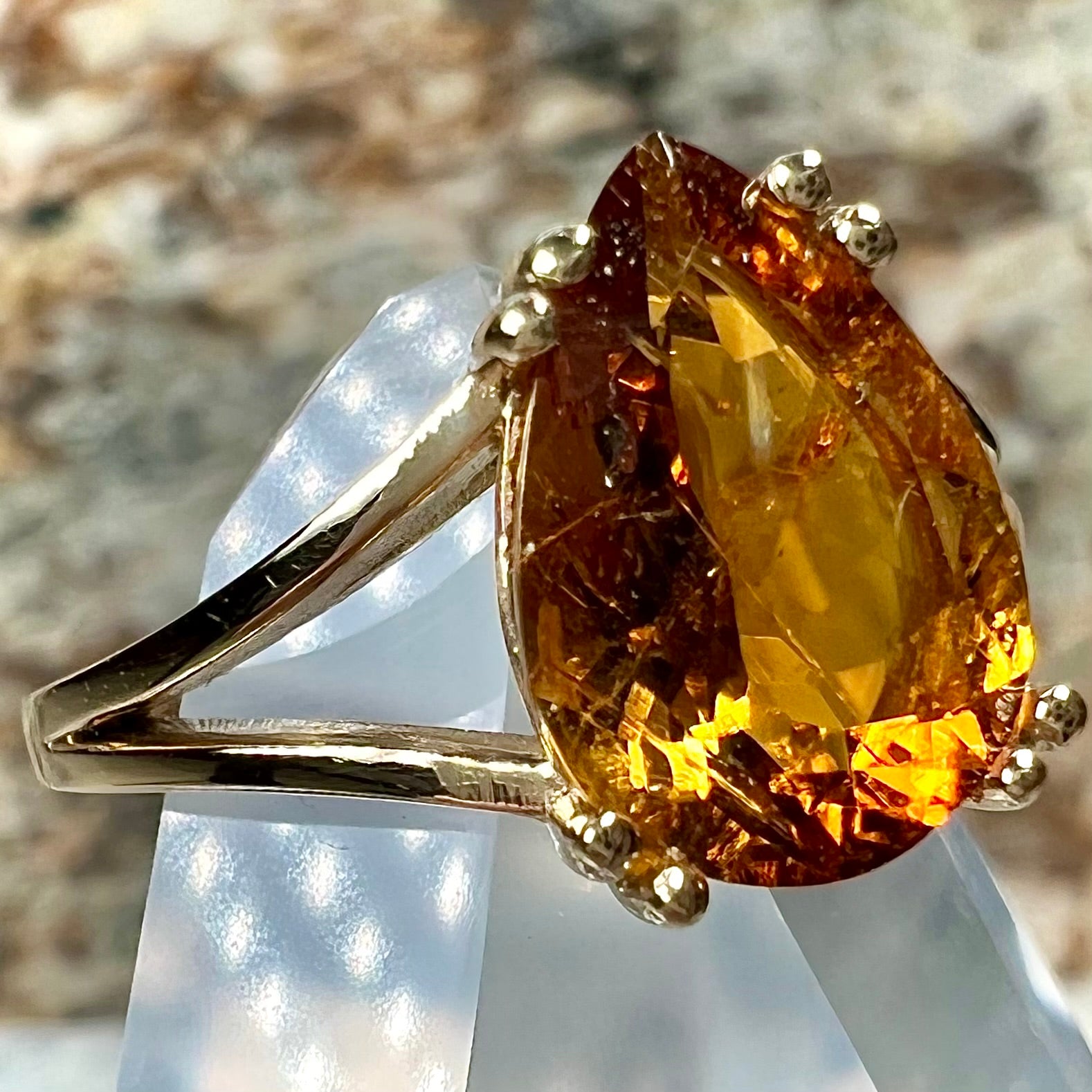 A gold split Euro shank solitaire ring set with an orange pear shape hessonite garnet stone.