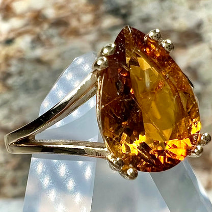 A gold split Euro shank solitaire ring set with an orange pear shape hessonite garnet stone.