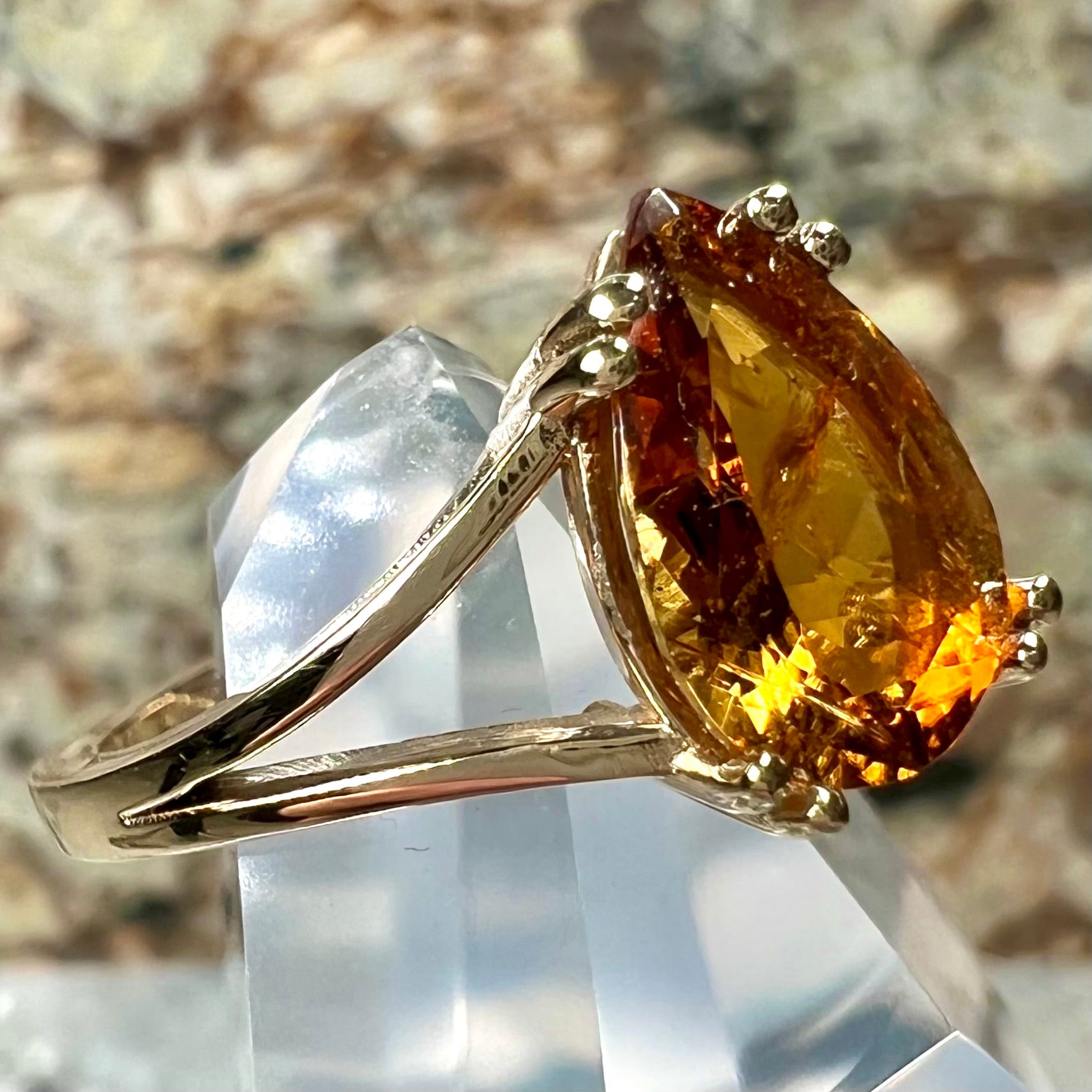 A gold split Euro shank solitaire ring set with an orange pear shape hessonite garnet stone.