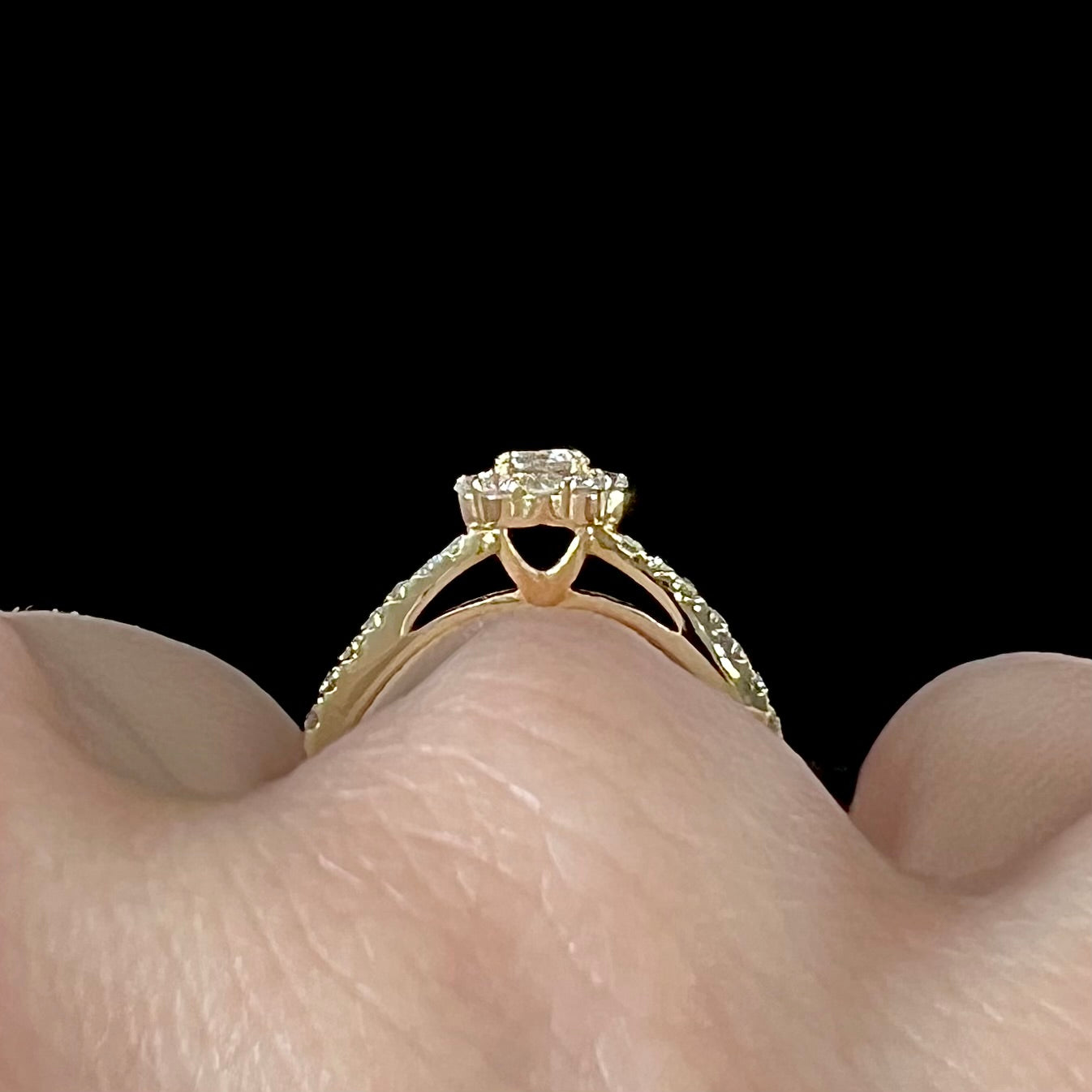 A ladies' diamond halo engagement ring cast in yellow gold.  The center stone is a 0.19ct round cut natural diamond.