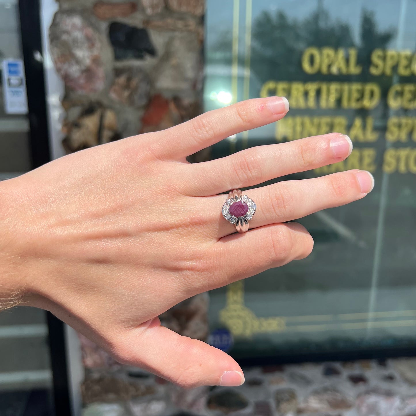 A natural, faceted oval cut ruby ring cast in sterling silver and set with cubic zirconia accents.