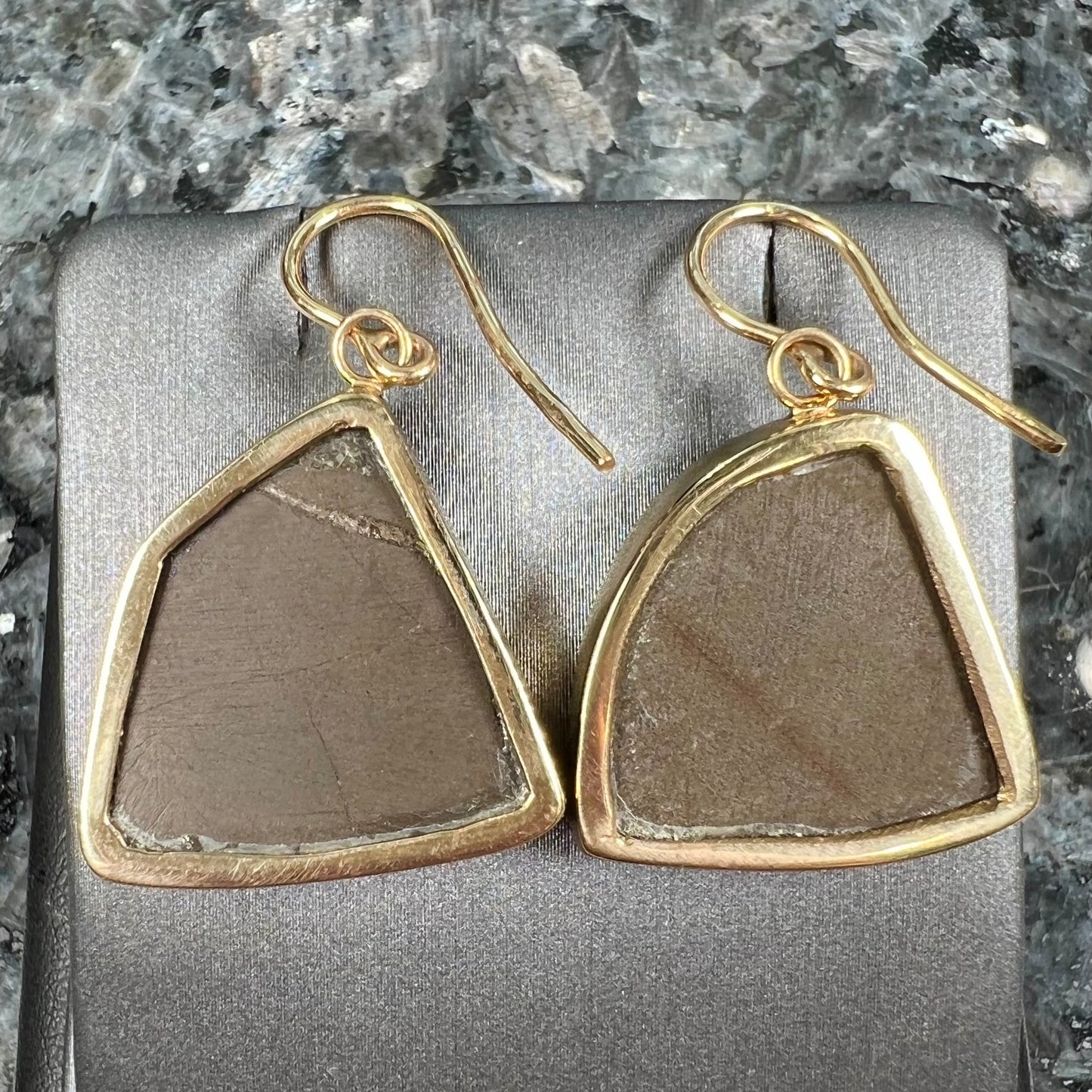Yellow gold French wire dangle earrings bezel set with two polished freeform cut red ammolite fossils.