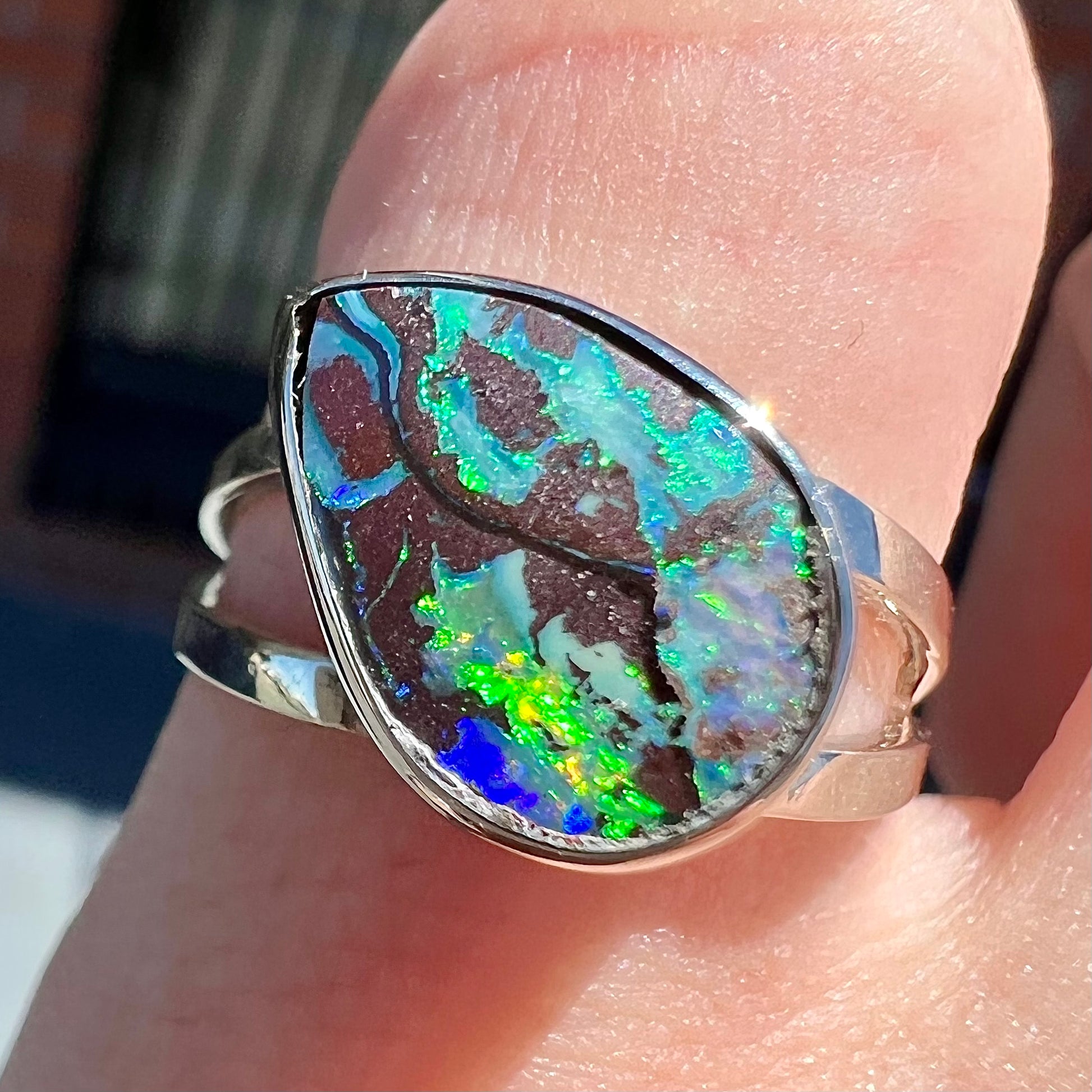 A split shank white gold boulder opal solitaire ring.  The stone has a natural hematite seam that runs through it.