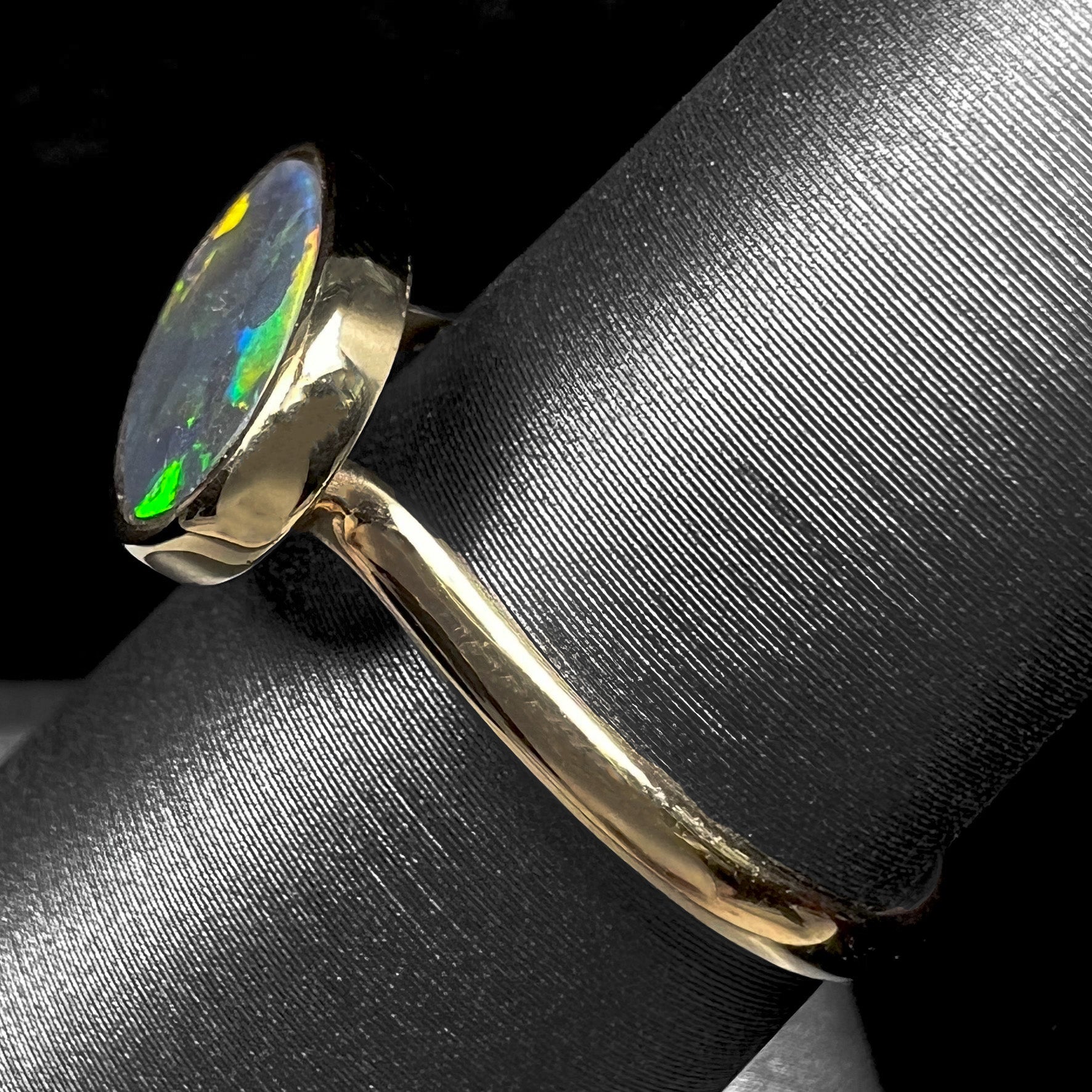 A ladies' yellow gold black opal solitaire ring from Lightning Ridge, Australia.