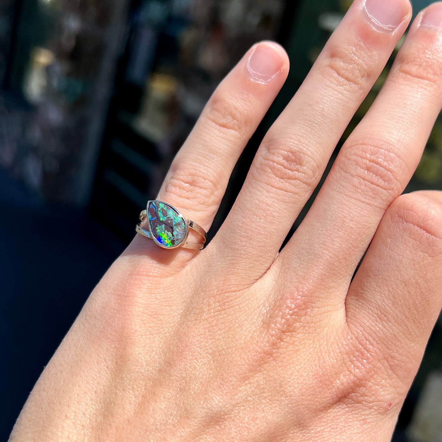 A split shank white gold boulder opal solitaire ring.  The stone has a natural hematite seam that runs through it.