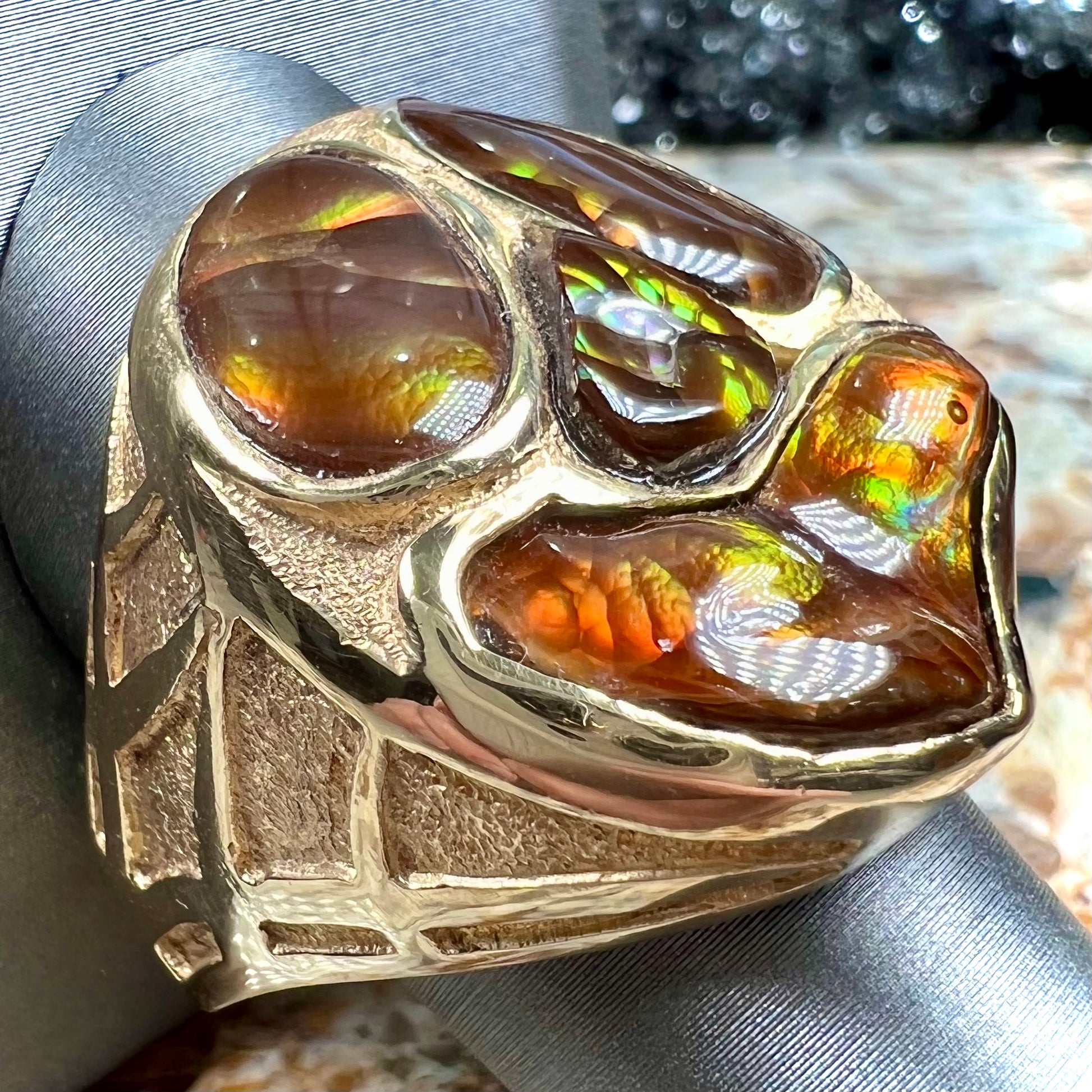 A yellow gold men's thug ring set with four fire agate stones resembling a spooky face.