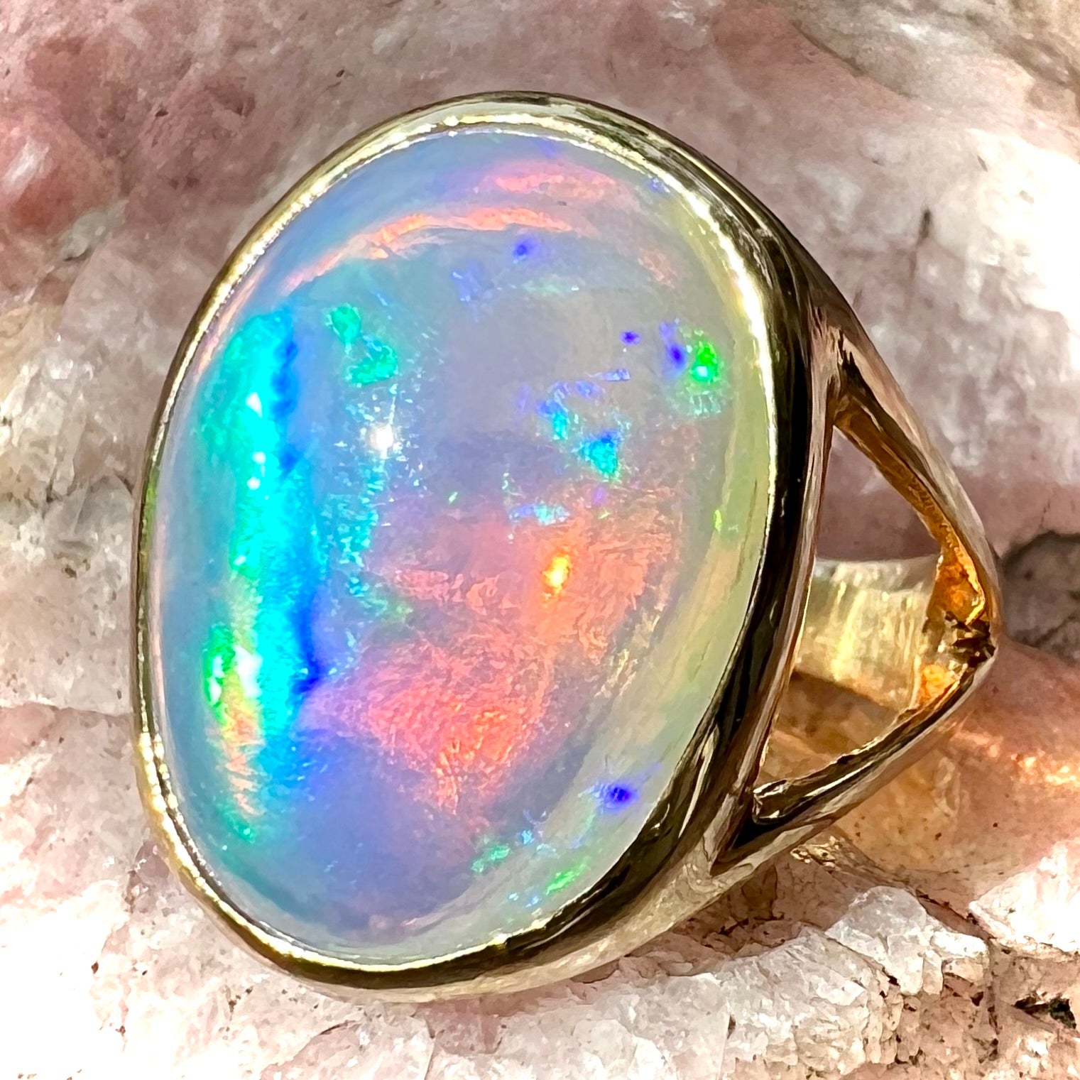 A gold split shank solitaire ring set with an oval cabochon cut 16.83 carat Ethiopian jelly fire opal.
