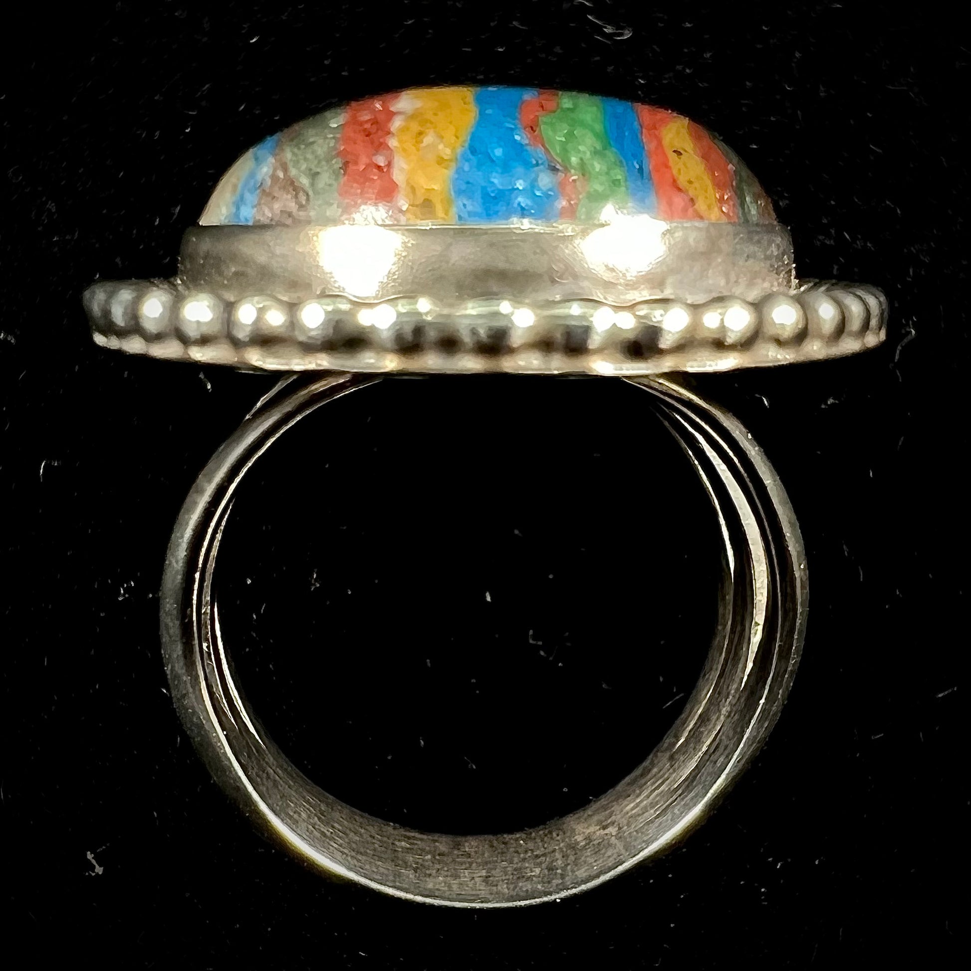 A split shank, rope bezel set silver ring set with an oval cut fordite paint stone.