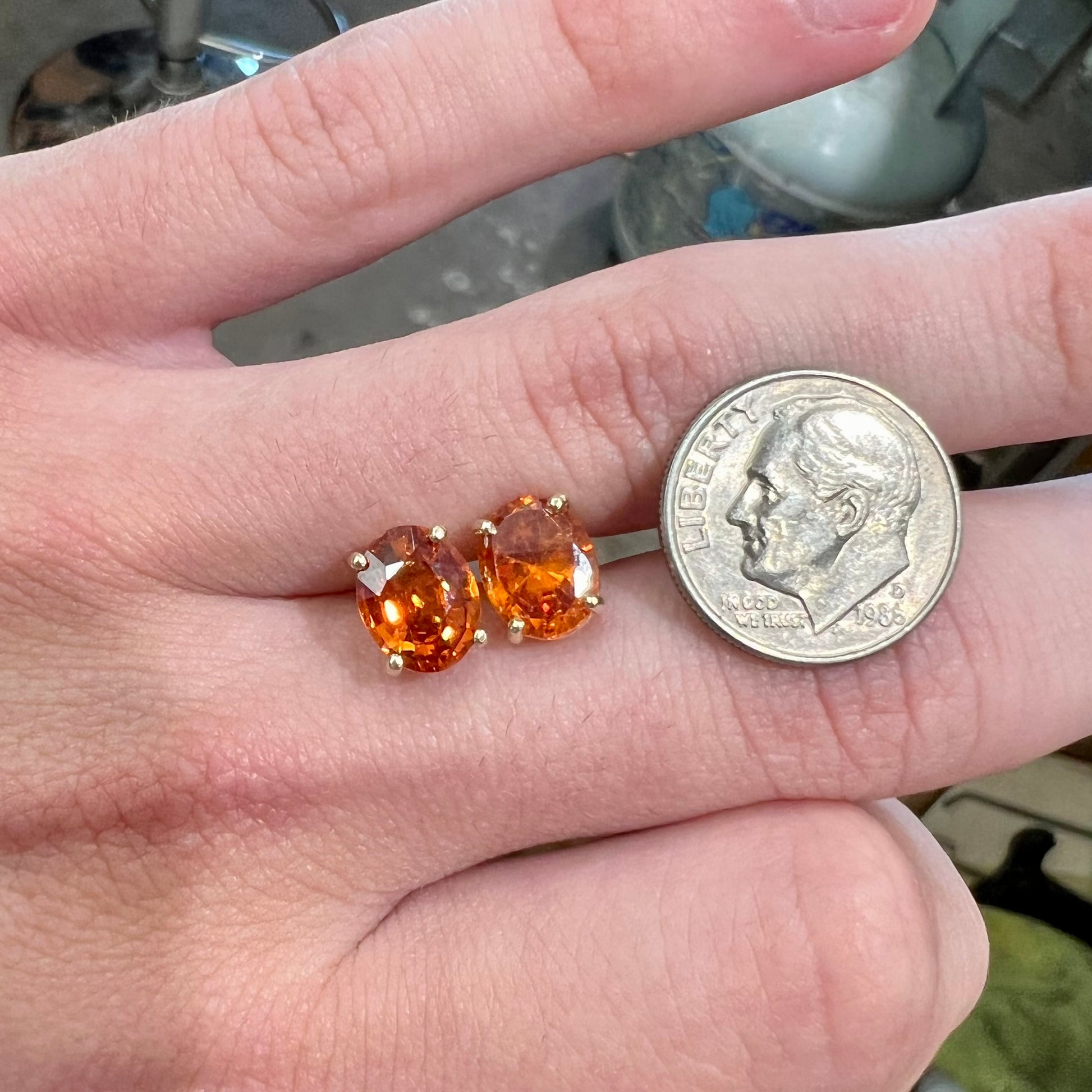 A pair of yellow gold orange hessonite garnet stud earrings.  The garnets are faceted oval cut.
