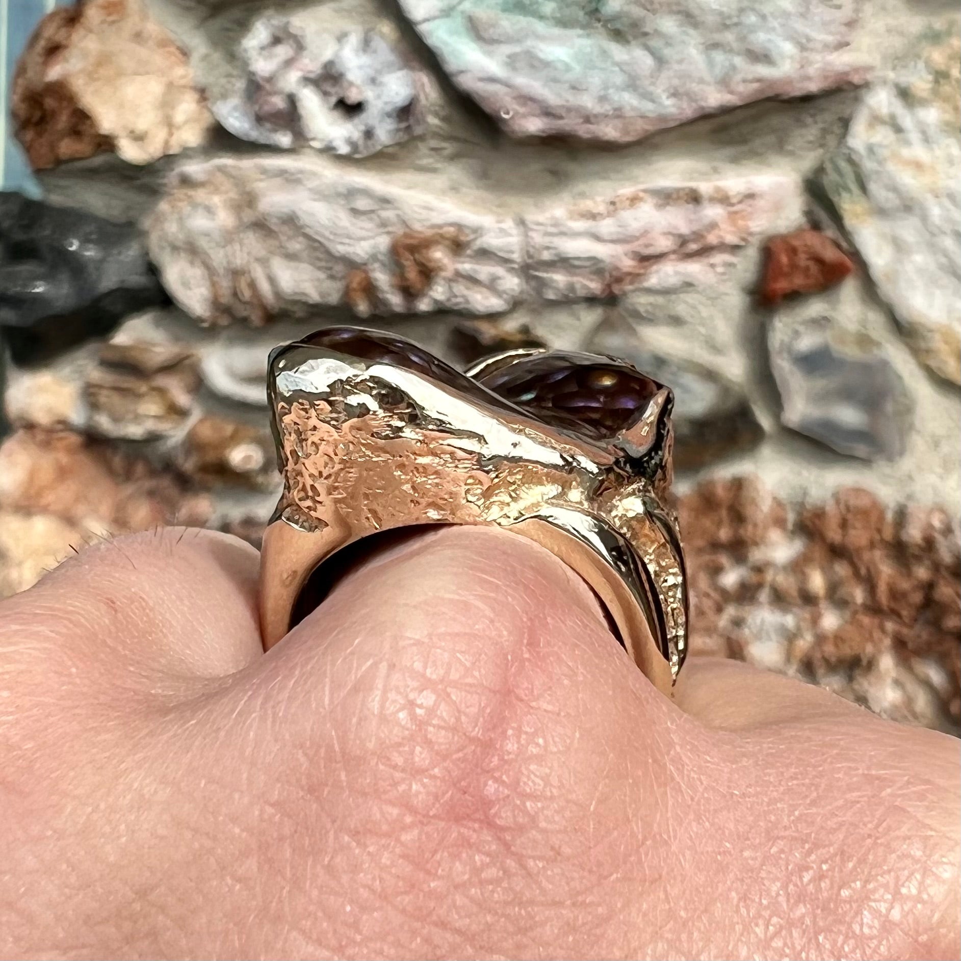 A men's Deer Creek fire agate solitaire ring cast in yellow gold.  The stone is predominantly purple.