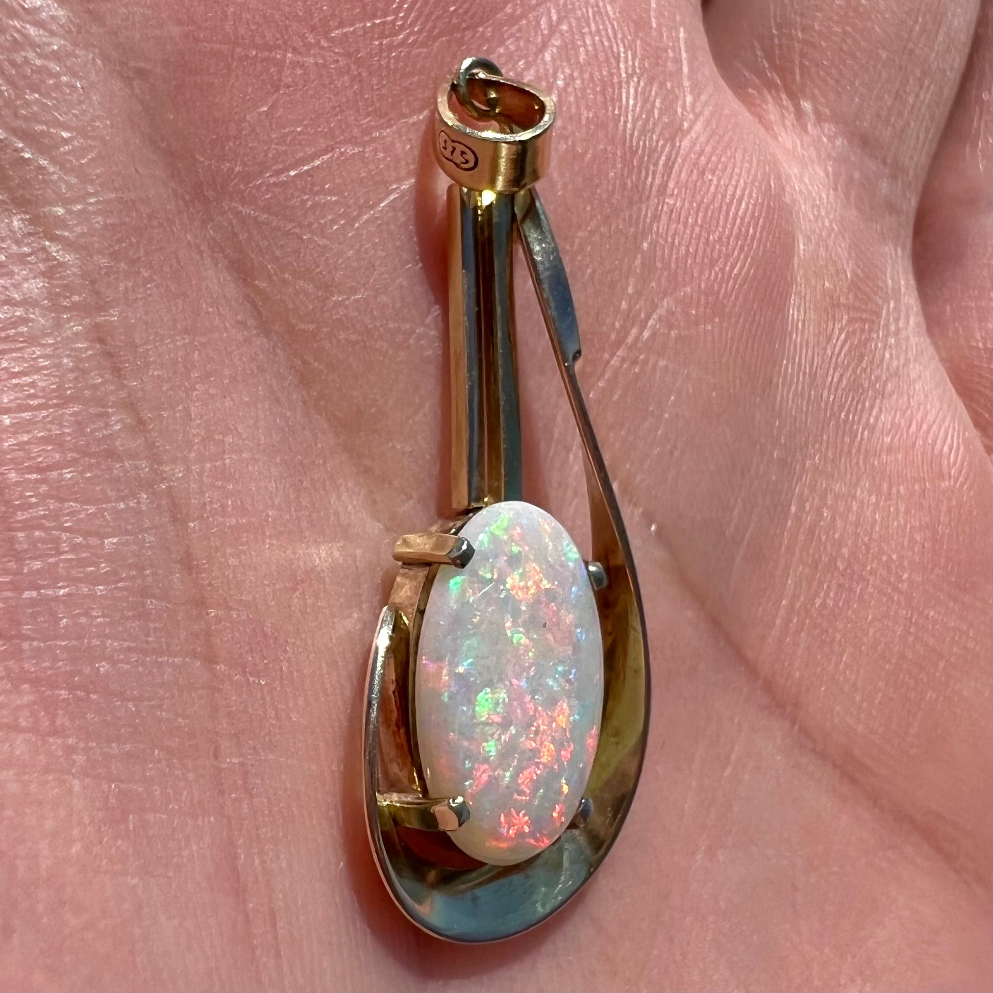 A handmade gold drop pendant set with an oval cabochon cut white crystal opal.