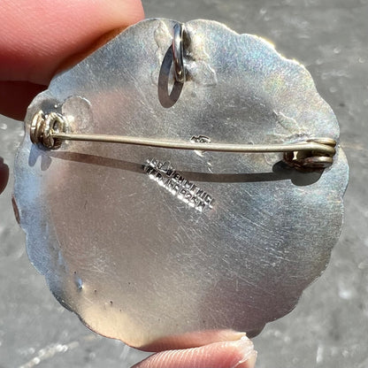 A sterling silver pendant/brooch bezel set with a round cabochon cut black sheen obsidian stone.